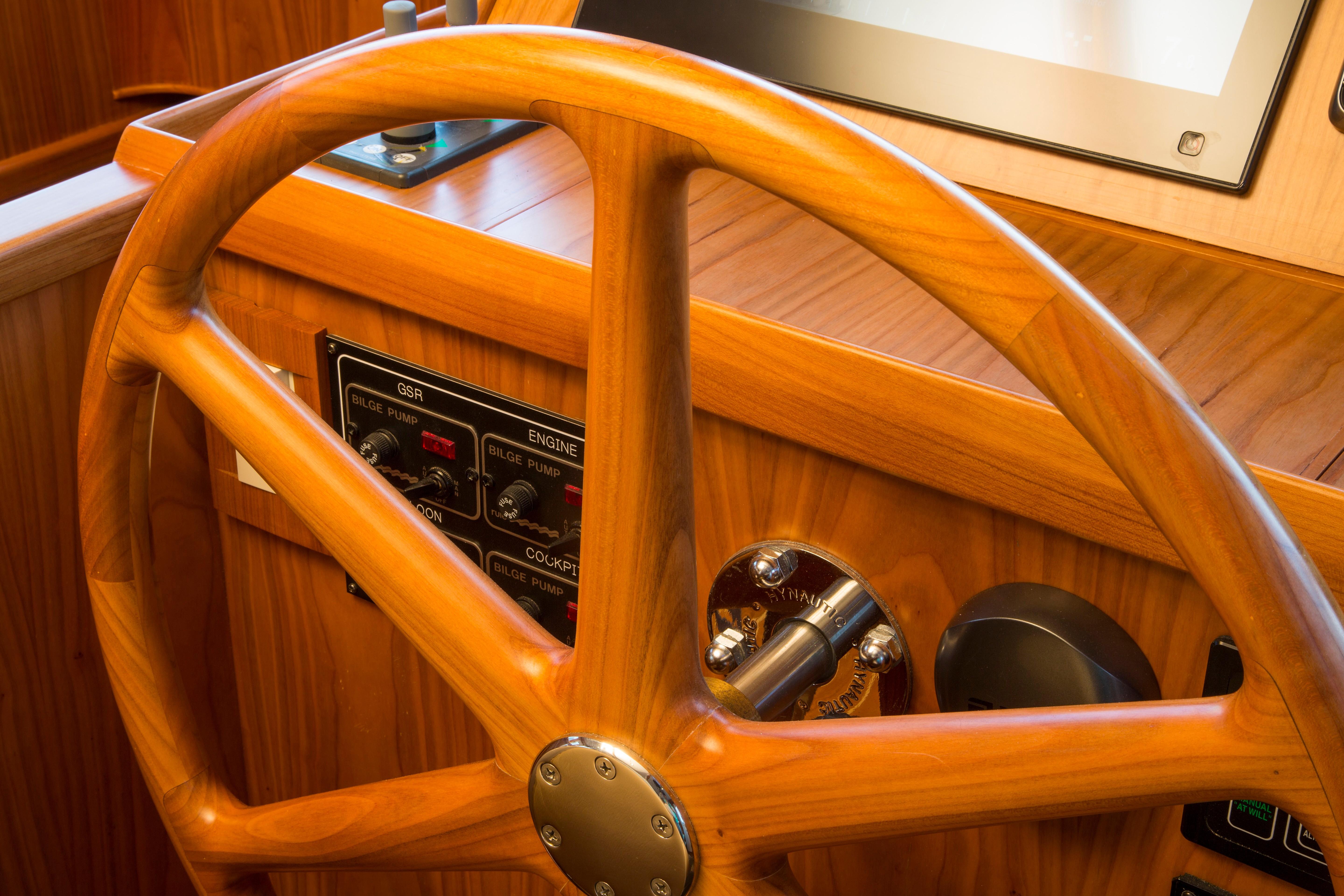 Wooden helm of 2026 Krogen Express 52' yacht, featuring control panel and steering wheel.