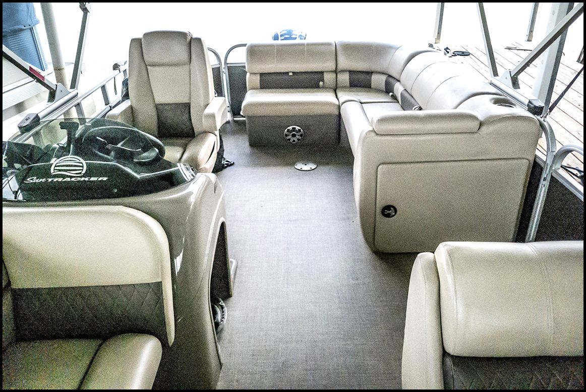 Interior of a Sun Tracker Party Barge 20 DLX with beige seating and steering wheel.