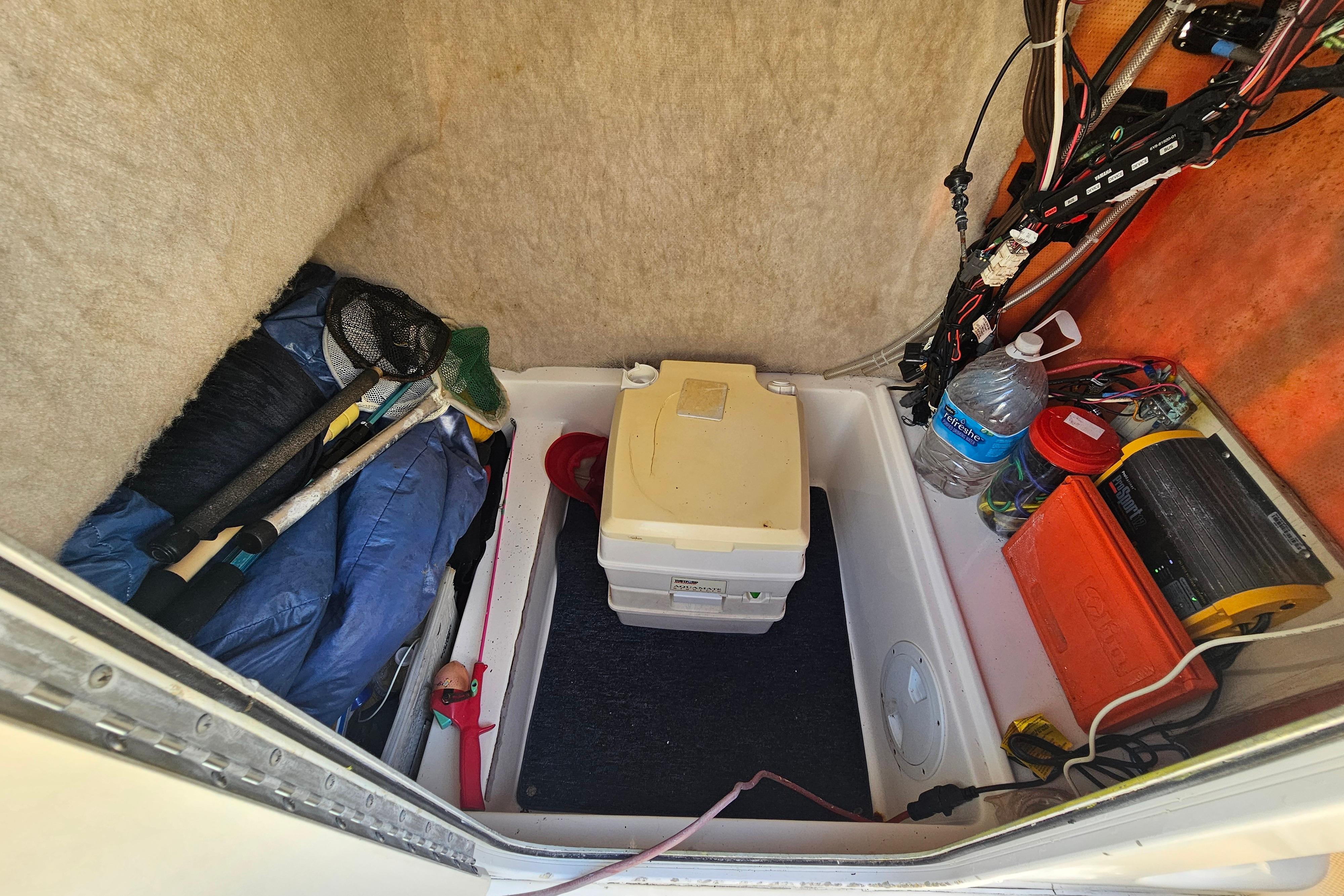 Storage compartment of a 2002 Sea Fox 210 Center Console boat with fishing gear and supplies.