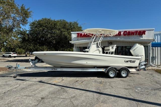 2026 Mako 24 APEX boat on trailer outside dealership, sunny day.