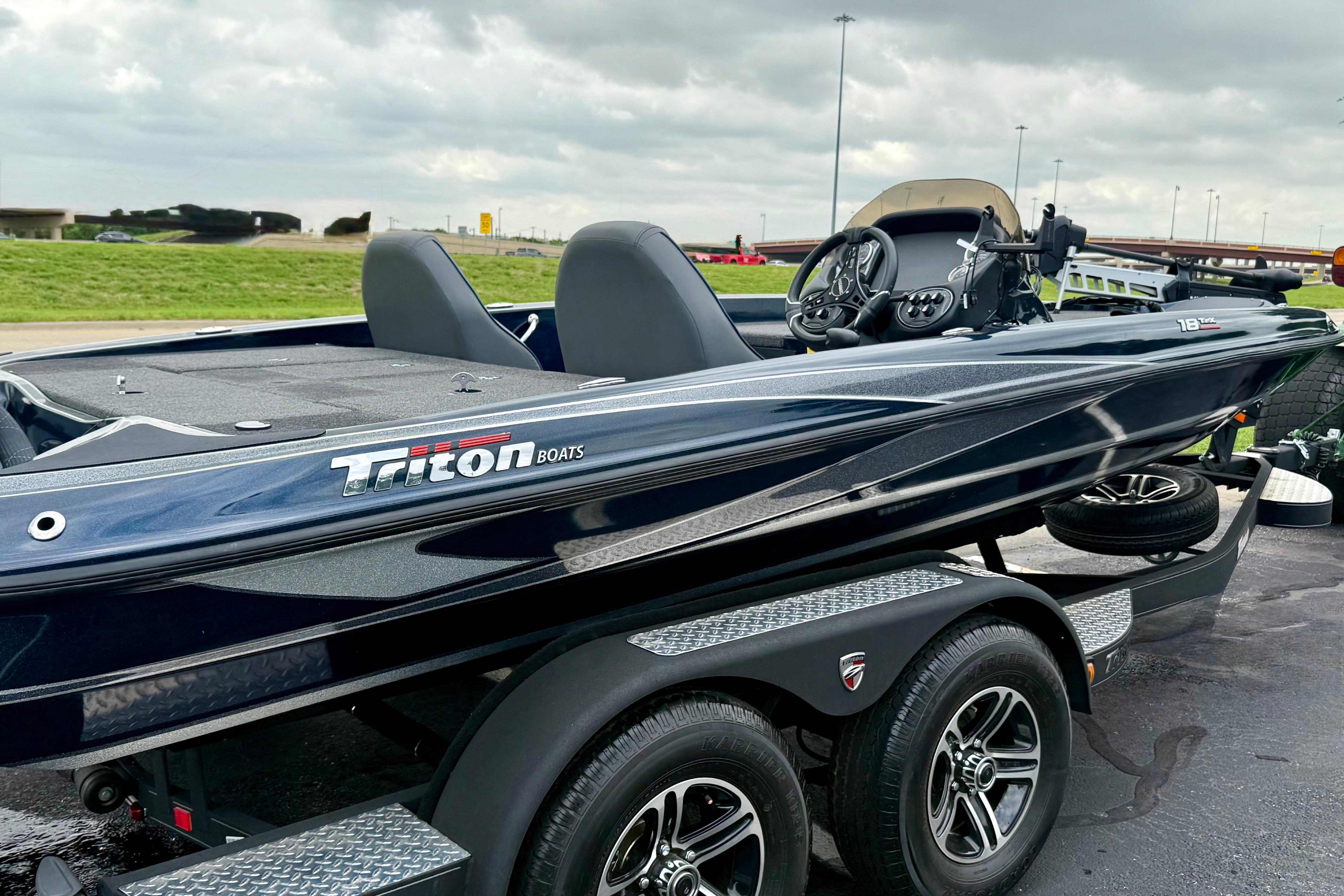 2023 Triton 18 TrX boat on trailer, sleek design, parked outdoors under cloudy sky.