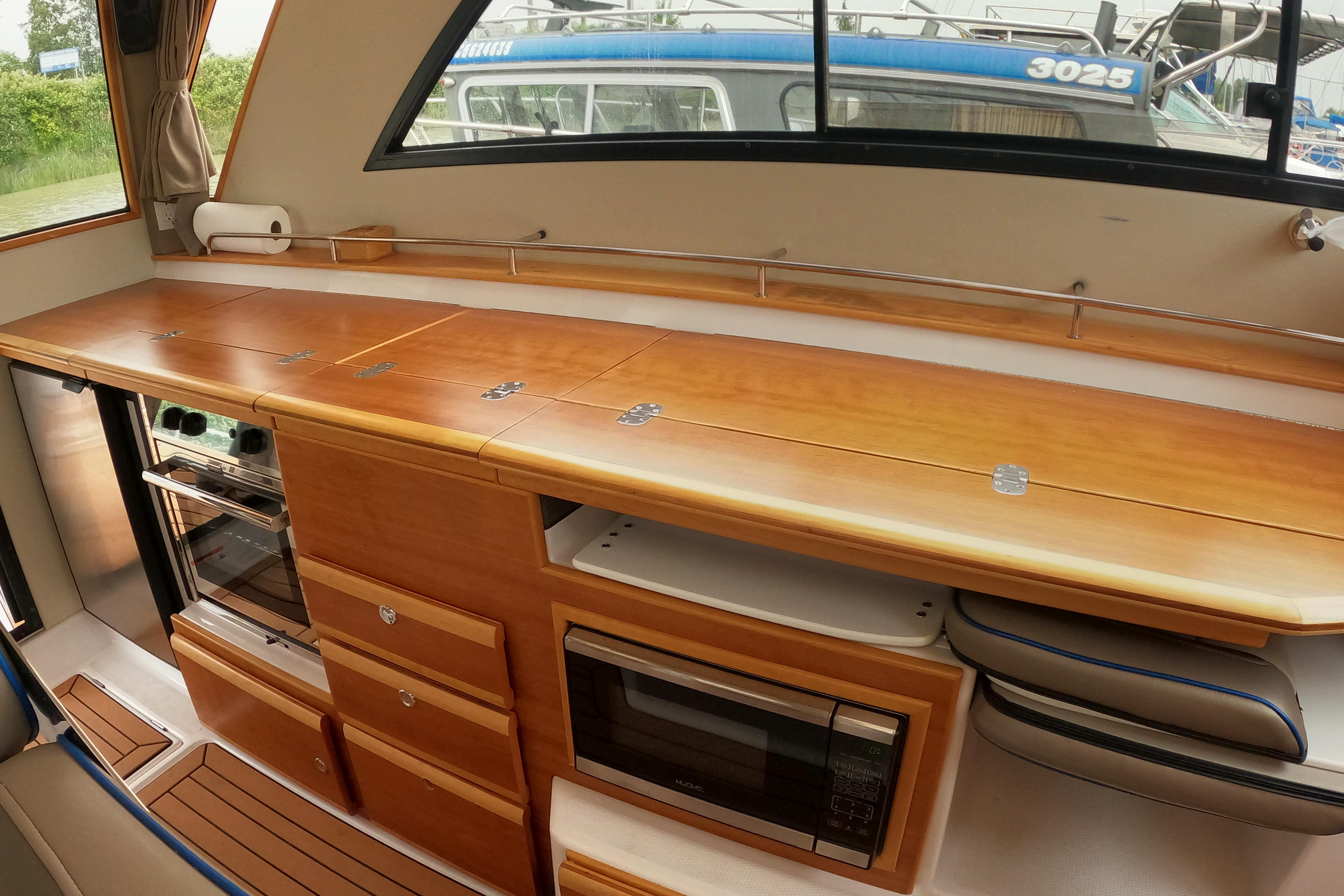 Interior of 2019 Cutwater C-30 Sedan, featuring a sleek wooden kitchen with modern appliances.