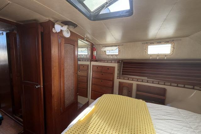 Interior of 1982 Lancer 45 Motorsailer with wooden cabinetry and cozy bedding.