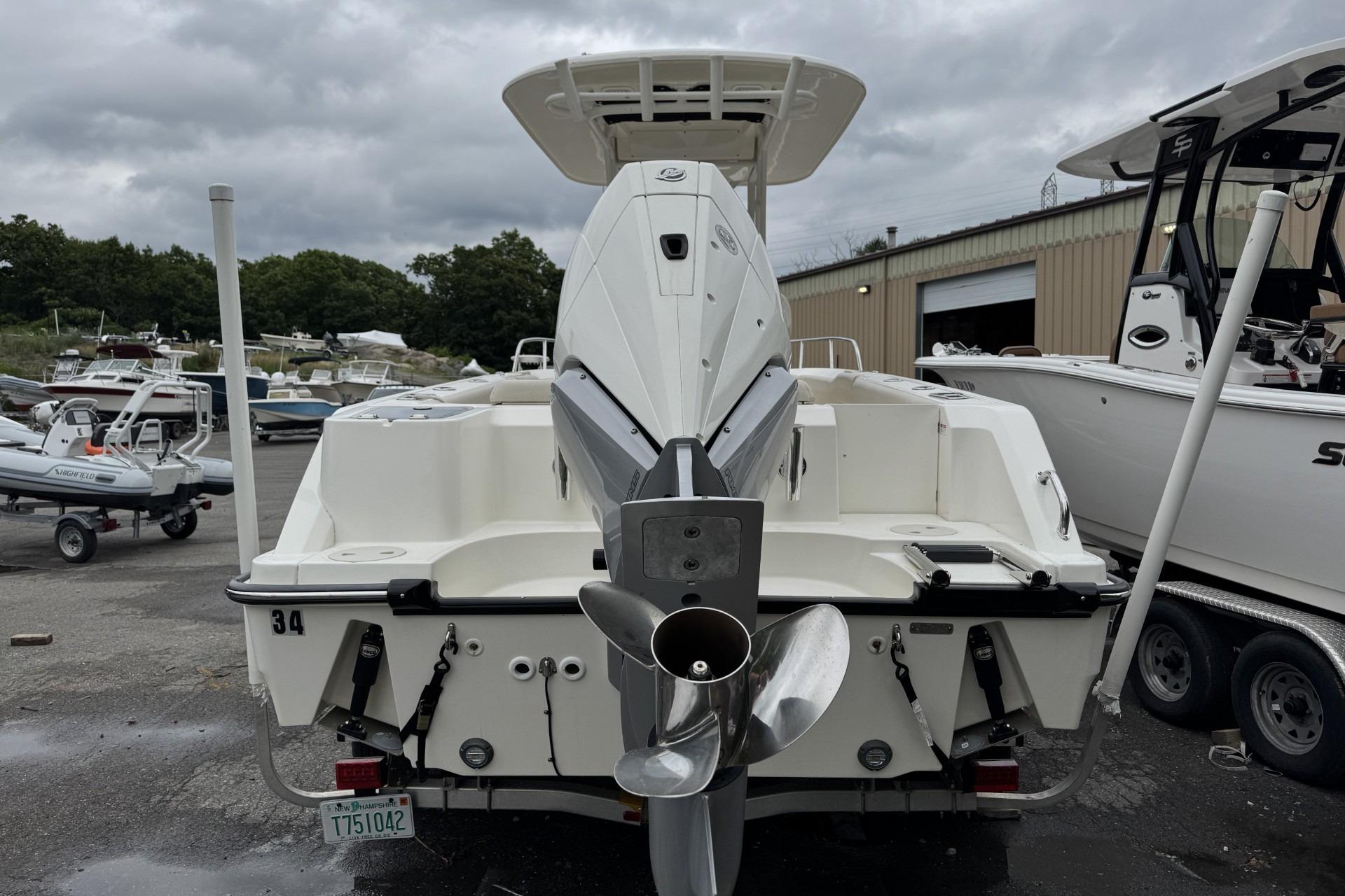 2024 Boston Whaler 230 Outrage boat, rear view with outboard motor, in a marina setting.