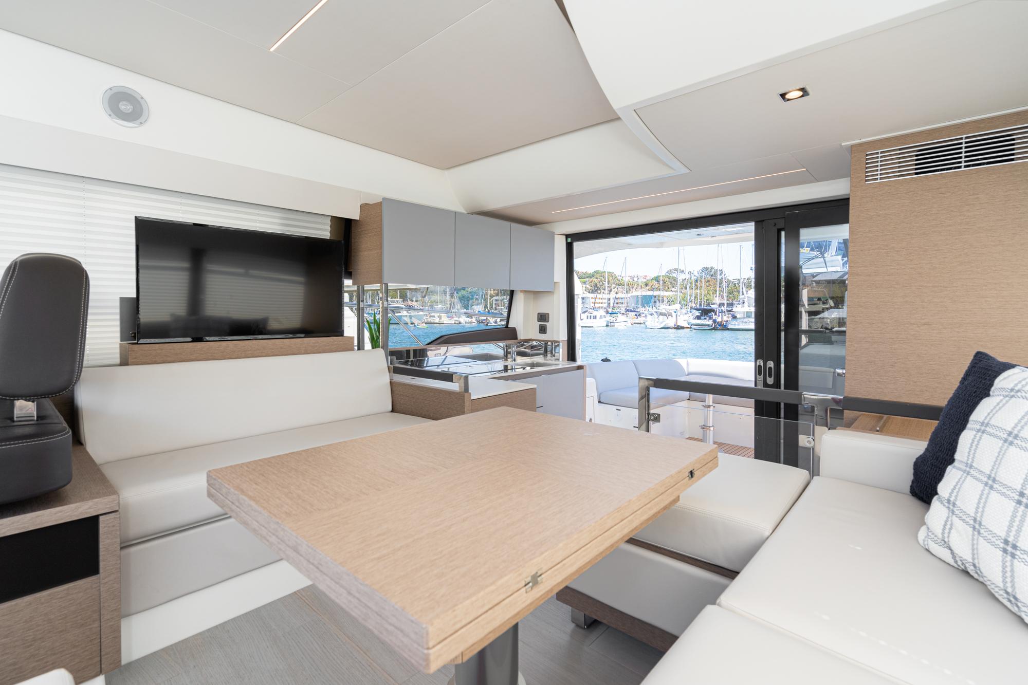 Modern interior of 2022 Prestige 460 yacht with dining area and marina view.