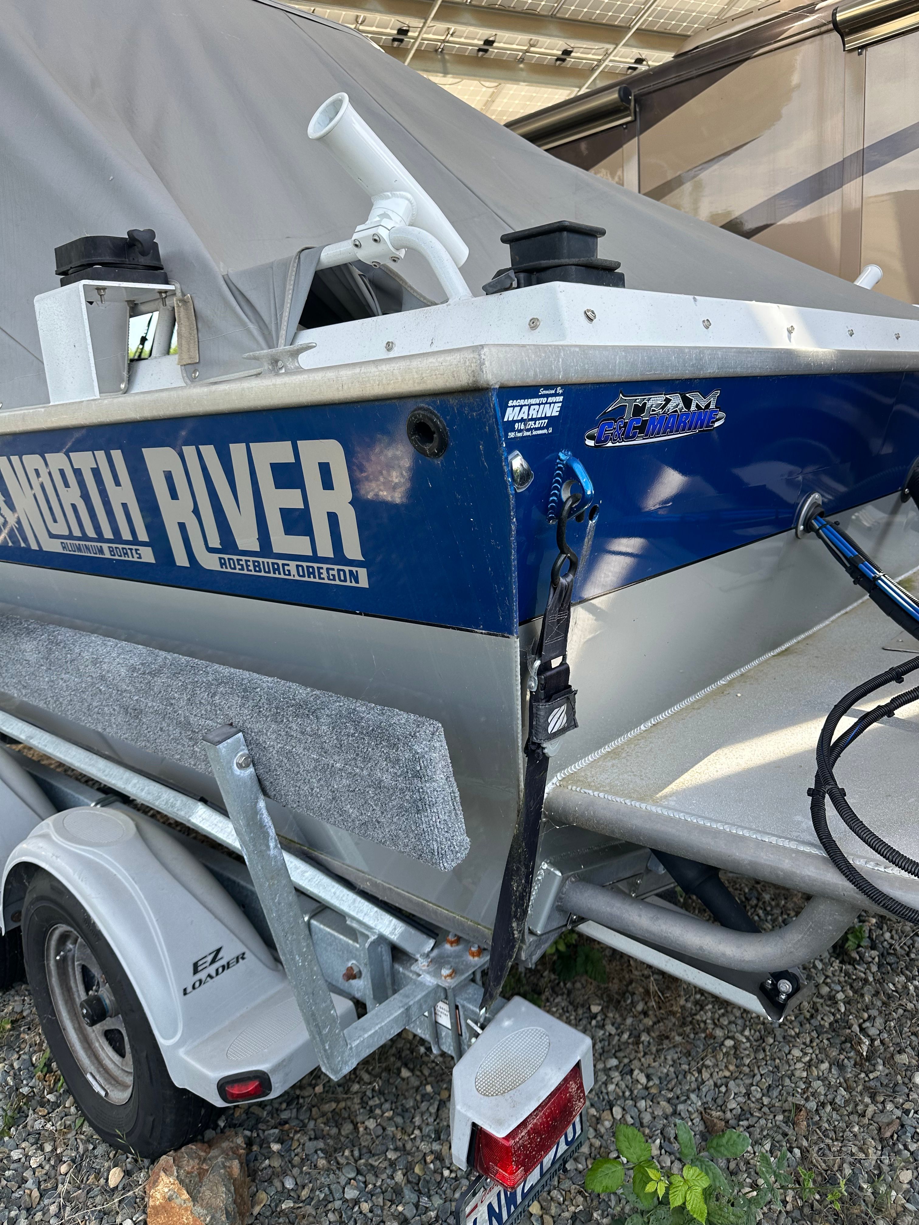 A 2006 North River aluminum boat on a trailer, partially covered with a tarp.
