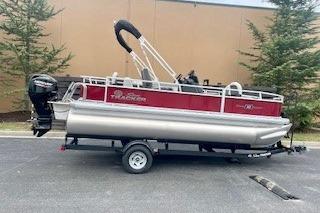 2026 Sun Tracker Bass Buggy 18 DLX pontoon boat on trailer, parked outdoors.