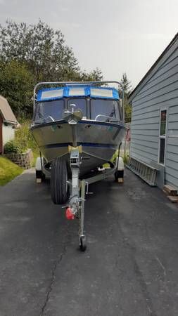 A Hewescraft Sea Runner 210 boat is on a trailer in a driveway.