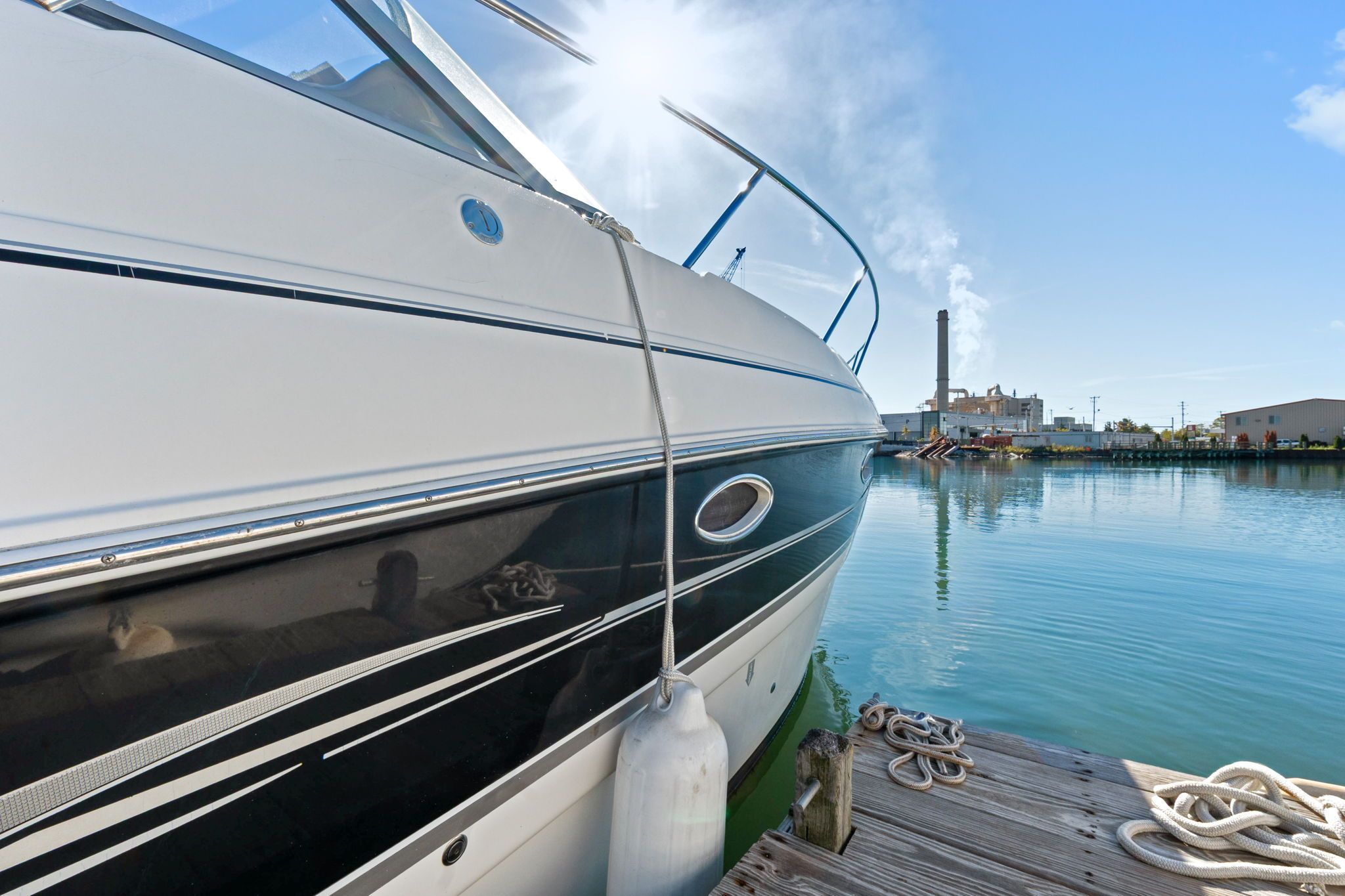 2007 Larson Cabrio 330 docked, with calm water and industrial buildings in the background.