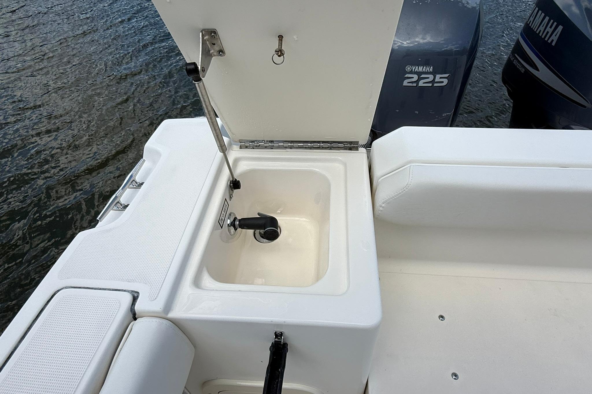 2003 Pursuit 2870 Walkaround boat with Yamaha 225 engine and open storage compartment.