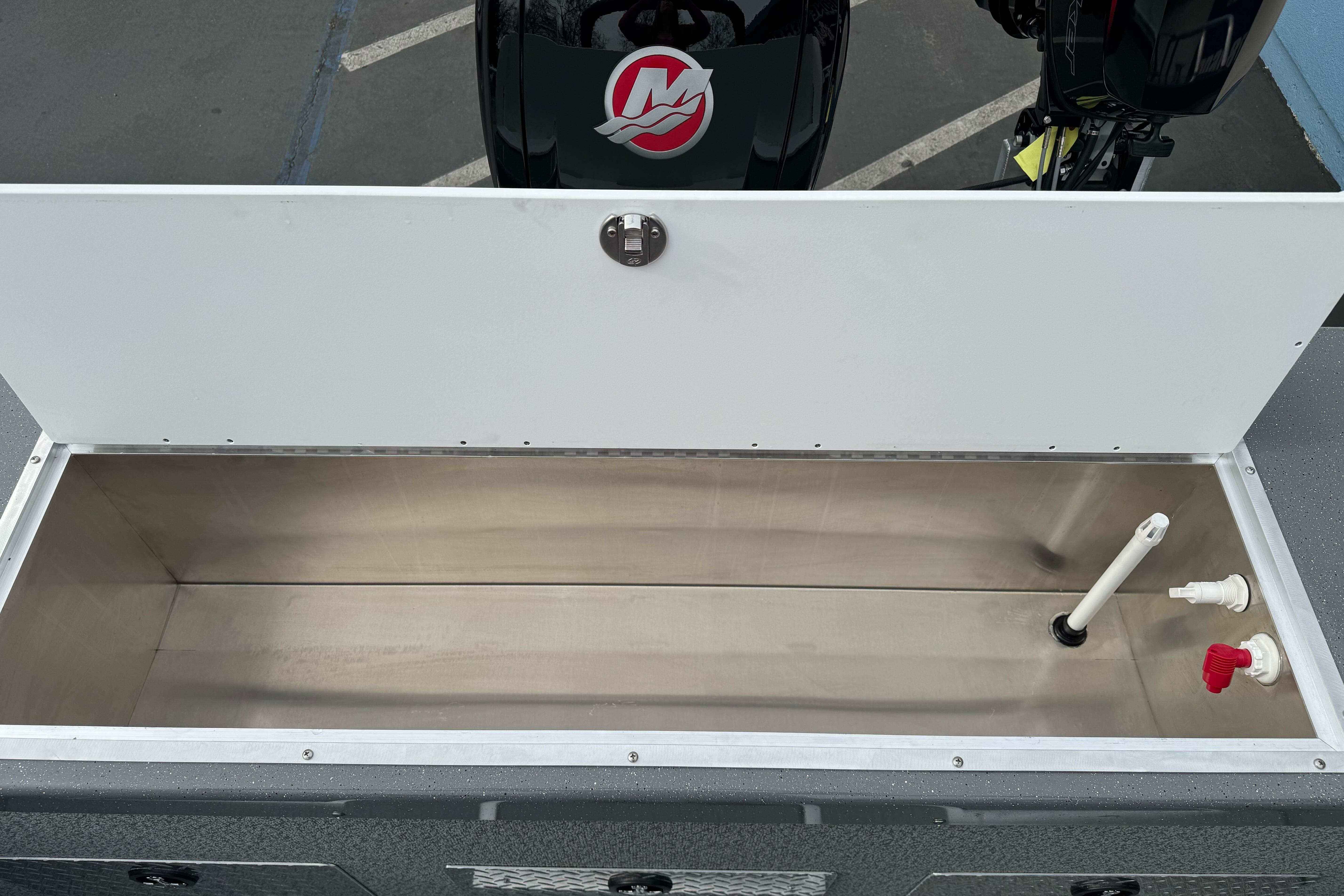 Open storage compartment in 2026 Lund 185 Heavy Gauge boat, featuring plumbing fixtures.