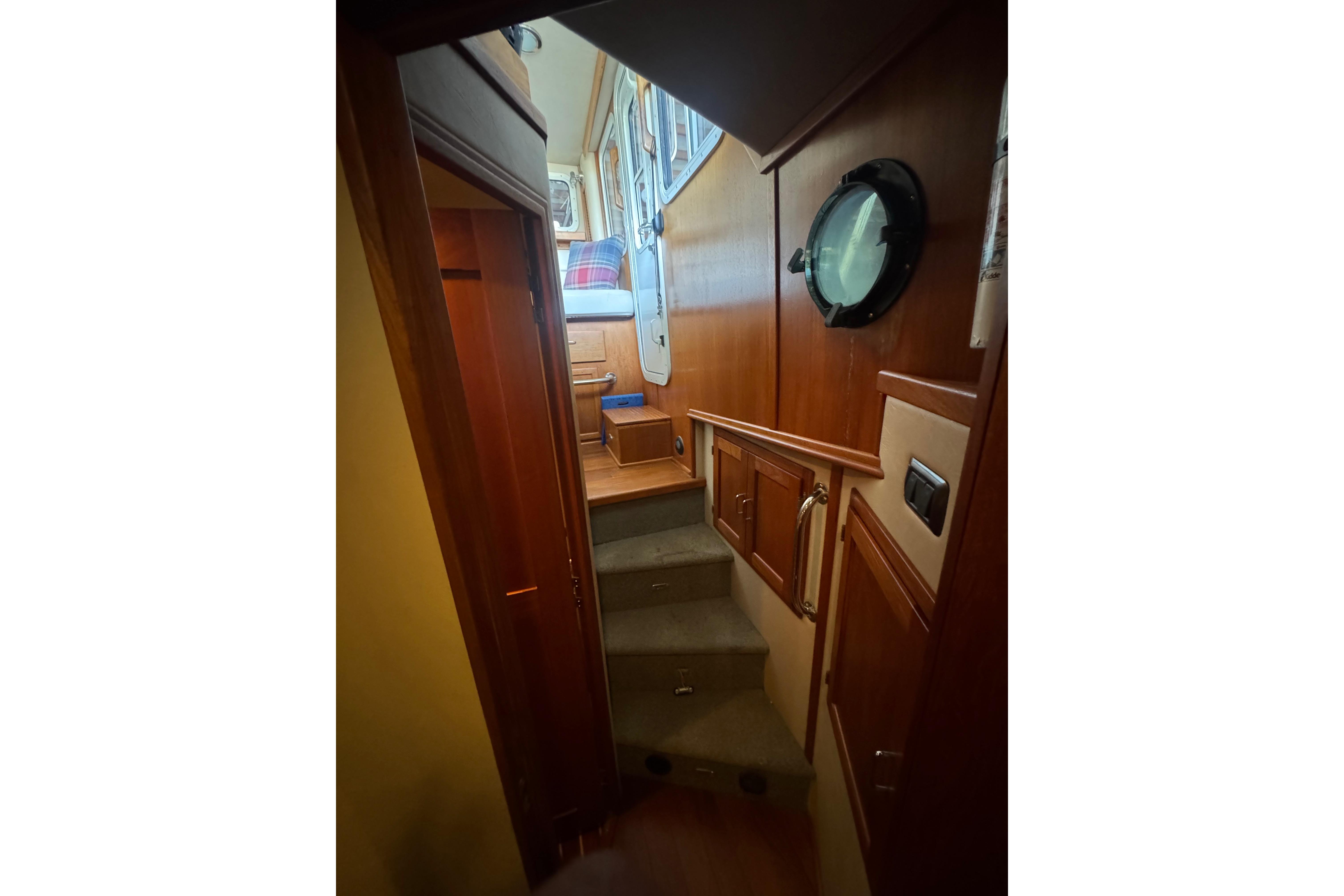 Interior view of 2005 American Tug 34, featuring wooden stairs and porthole.