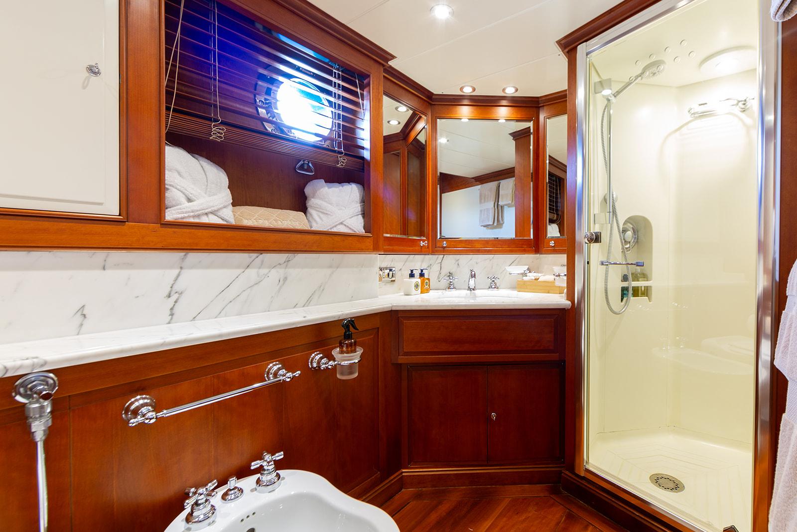 Luxurious yacht bathroom with wood accents, marble countertop, and glass shower, Perini Navi 37, 1996.