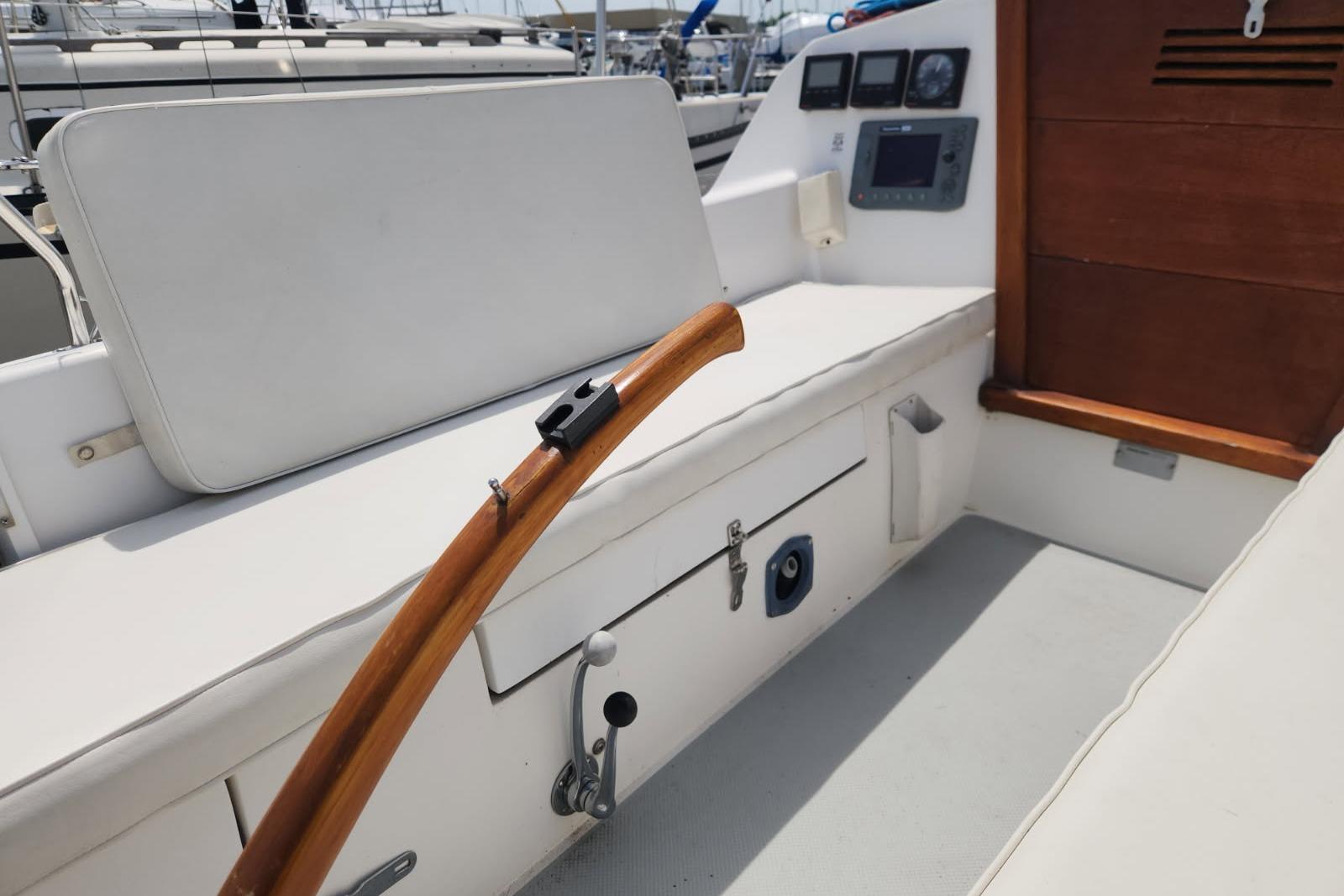 1990 Catalina Capri sailboat cockpit with wooden tiller and cushioned seating.