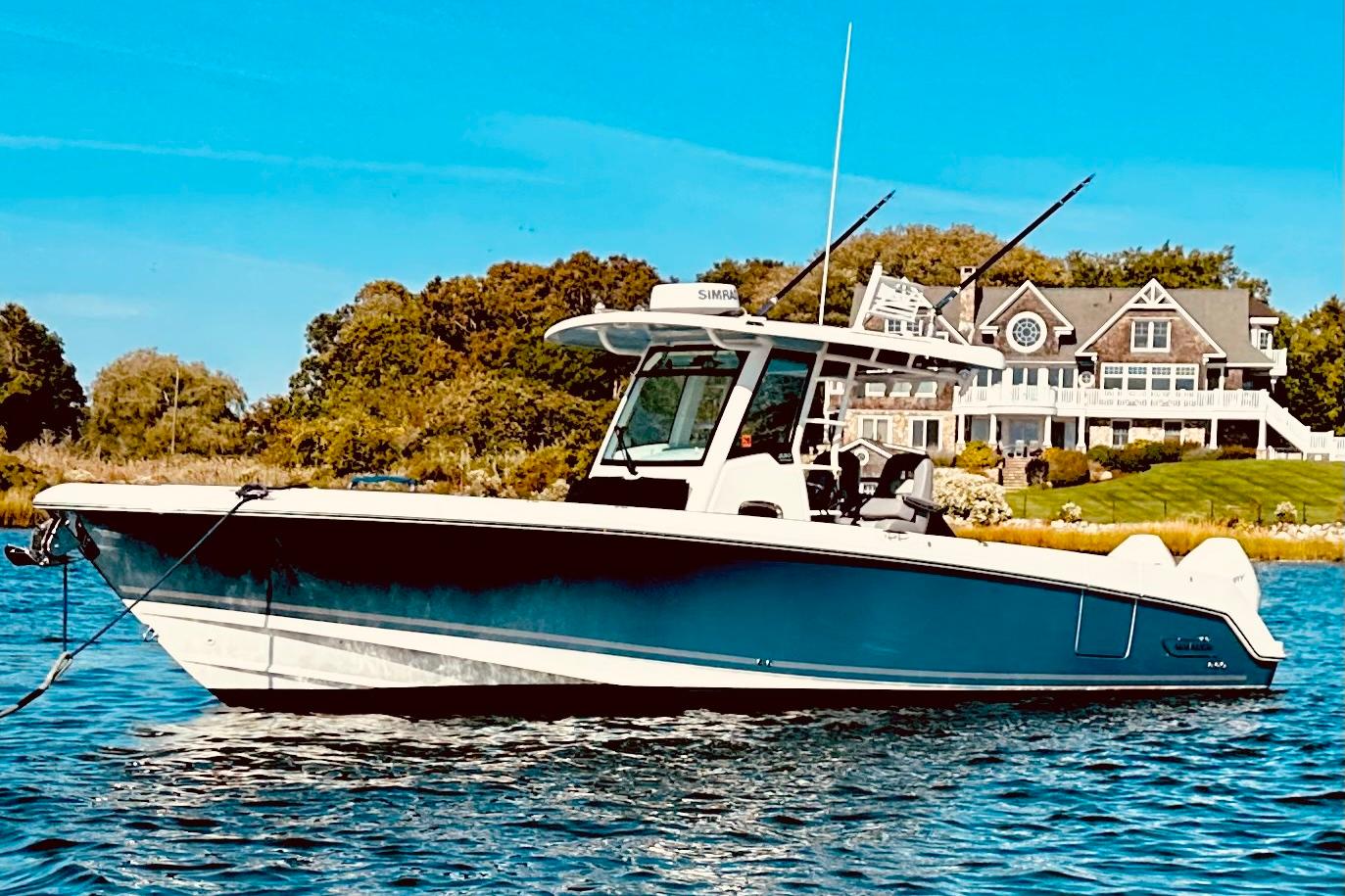 2023 Boston Whaler 330 Outrage boat on water, with a scenic house in the background.