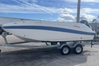 2022 Hurricane SunDeck 192 OB boat on trailer, parked outdoors under a cloudy sky.