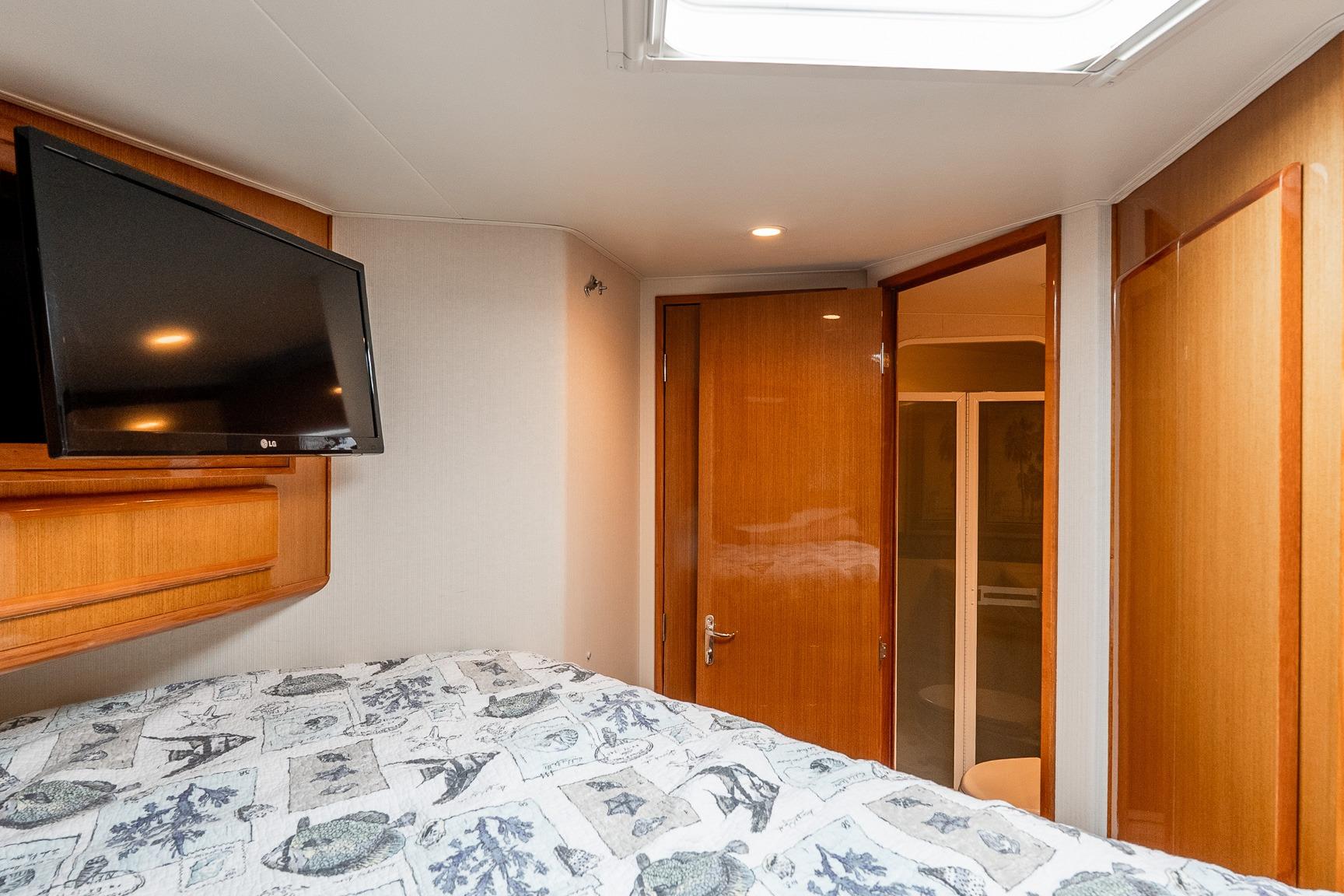 Interior of 2000 Viking 50' Convertible yacht bedroom with TV and wooden accents.