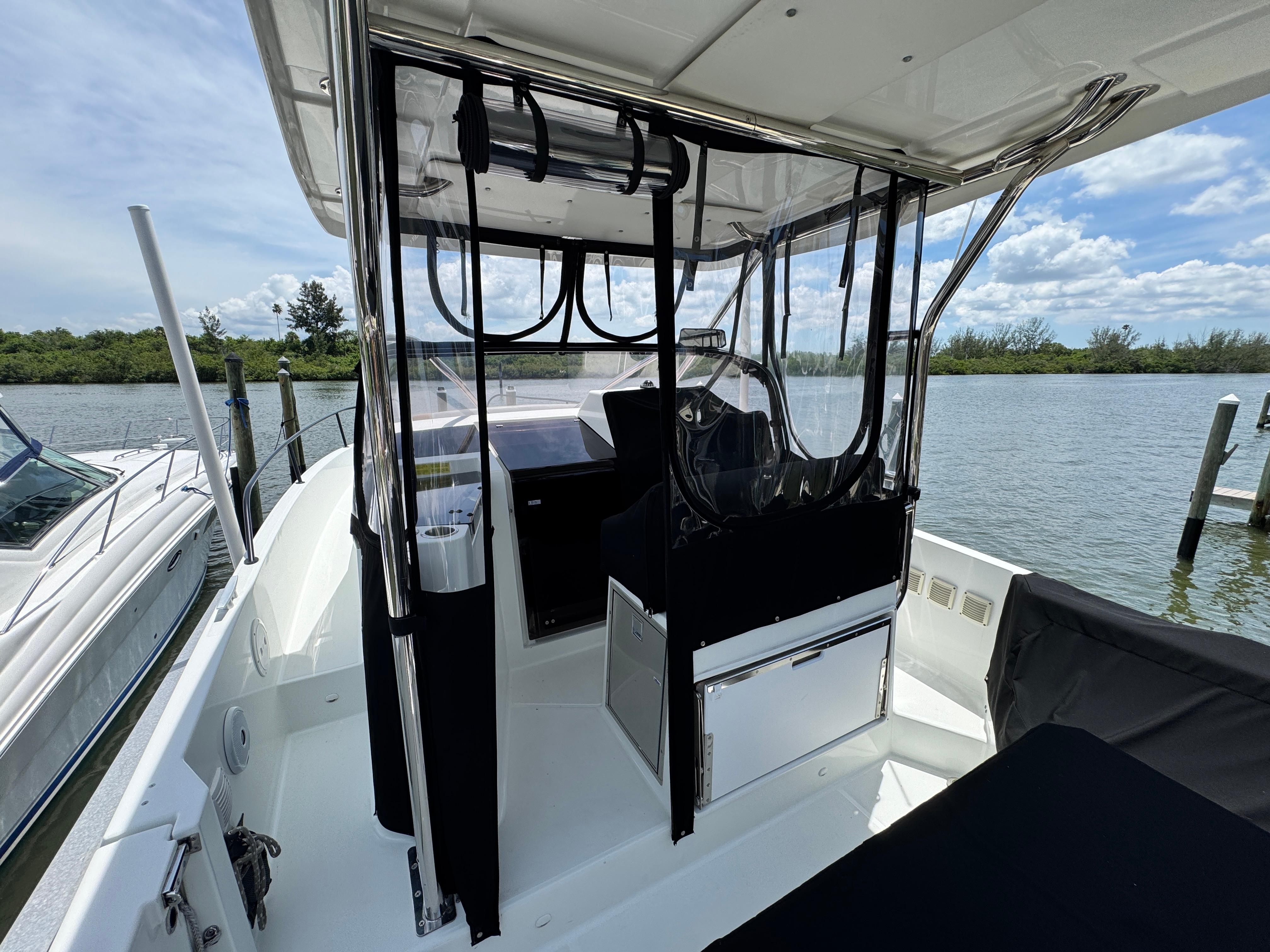 2022 Beneteau Flyer 9 SUNdeck boat interior with clear canopy, docked by a scenic waterway.