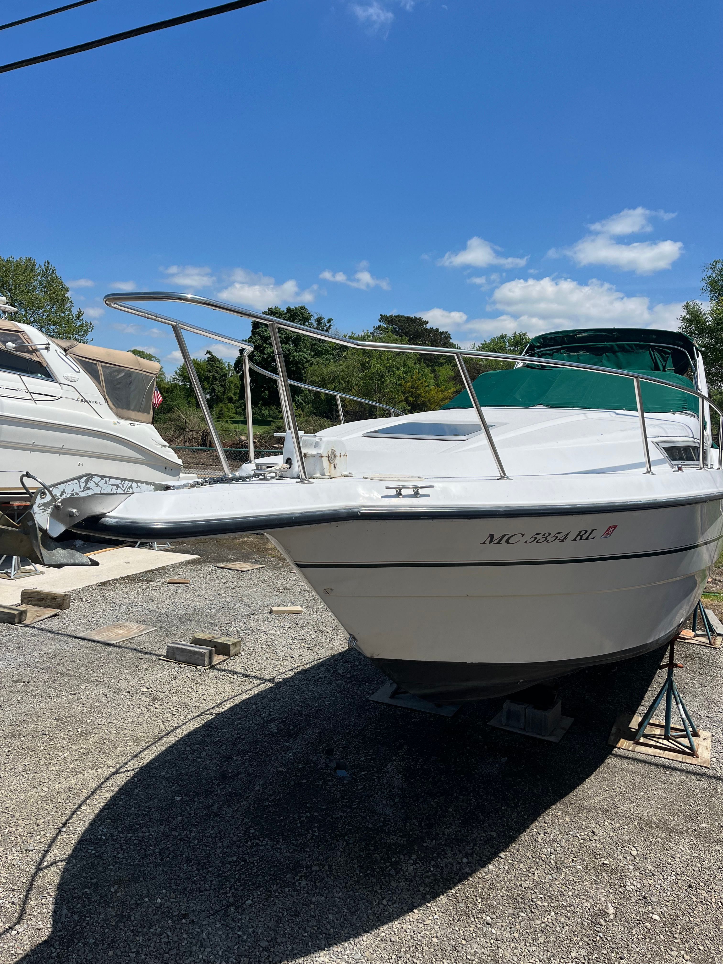 A white boat on a dry dock with a blue sky in the background.