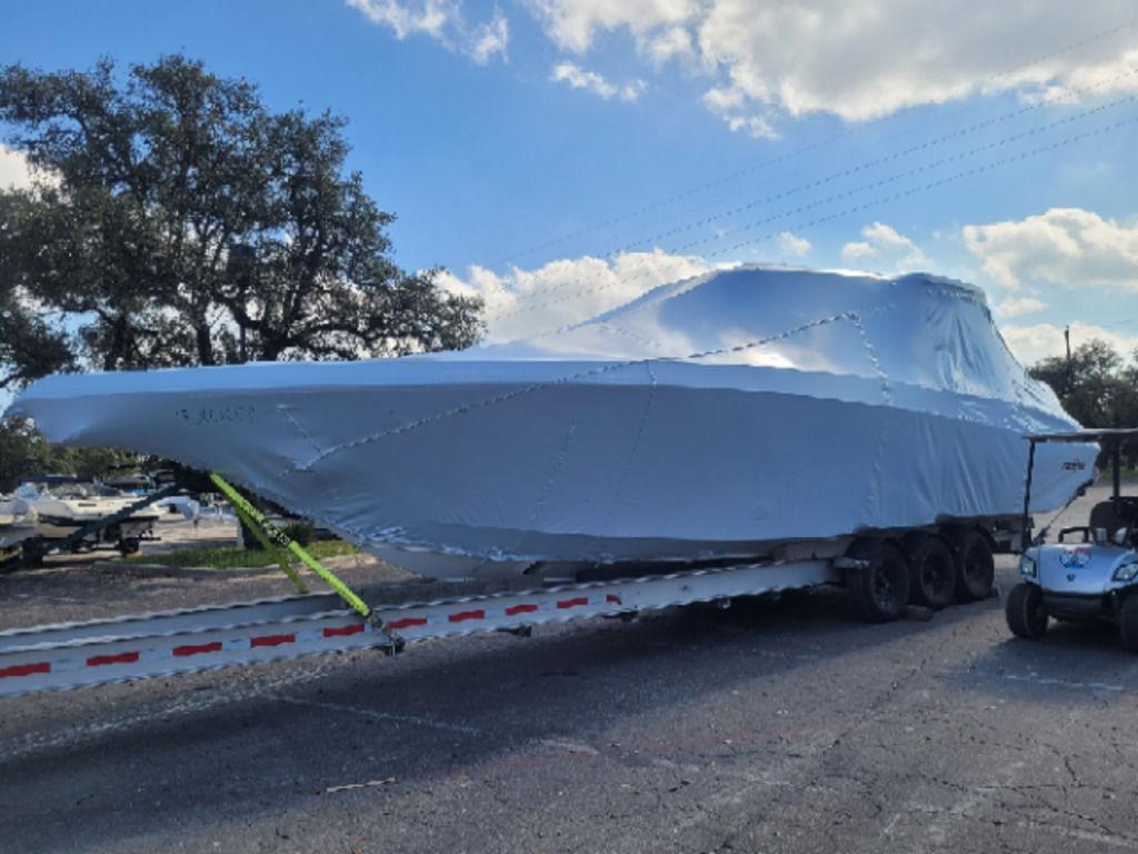 2024 Fountain 38 SCX boat covered on trailer under a cloudy sky.