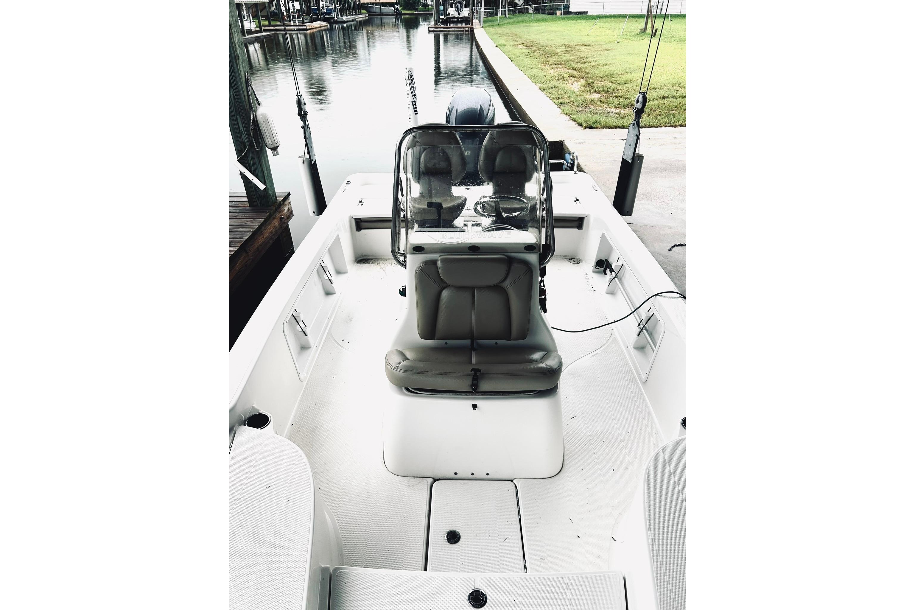 2017 Blue Wave 2200 PureBay boat interior with seating and console, docked by a calm waterway.