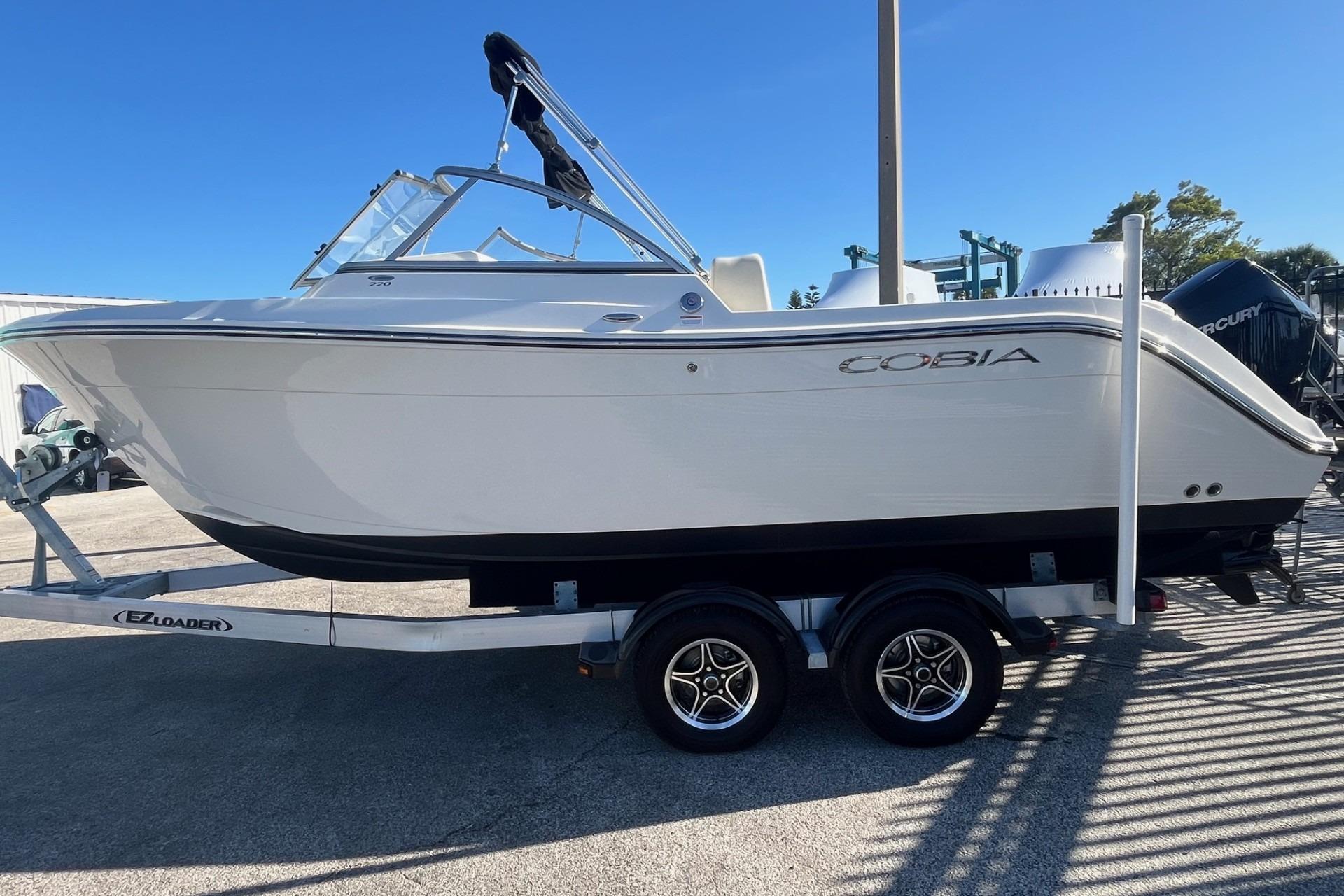 2023 Cobia 220 Dual Console boat on trailer, side view, clear sky background.