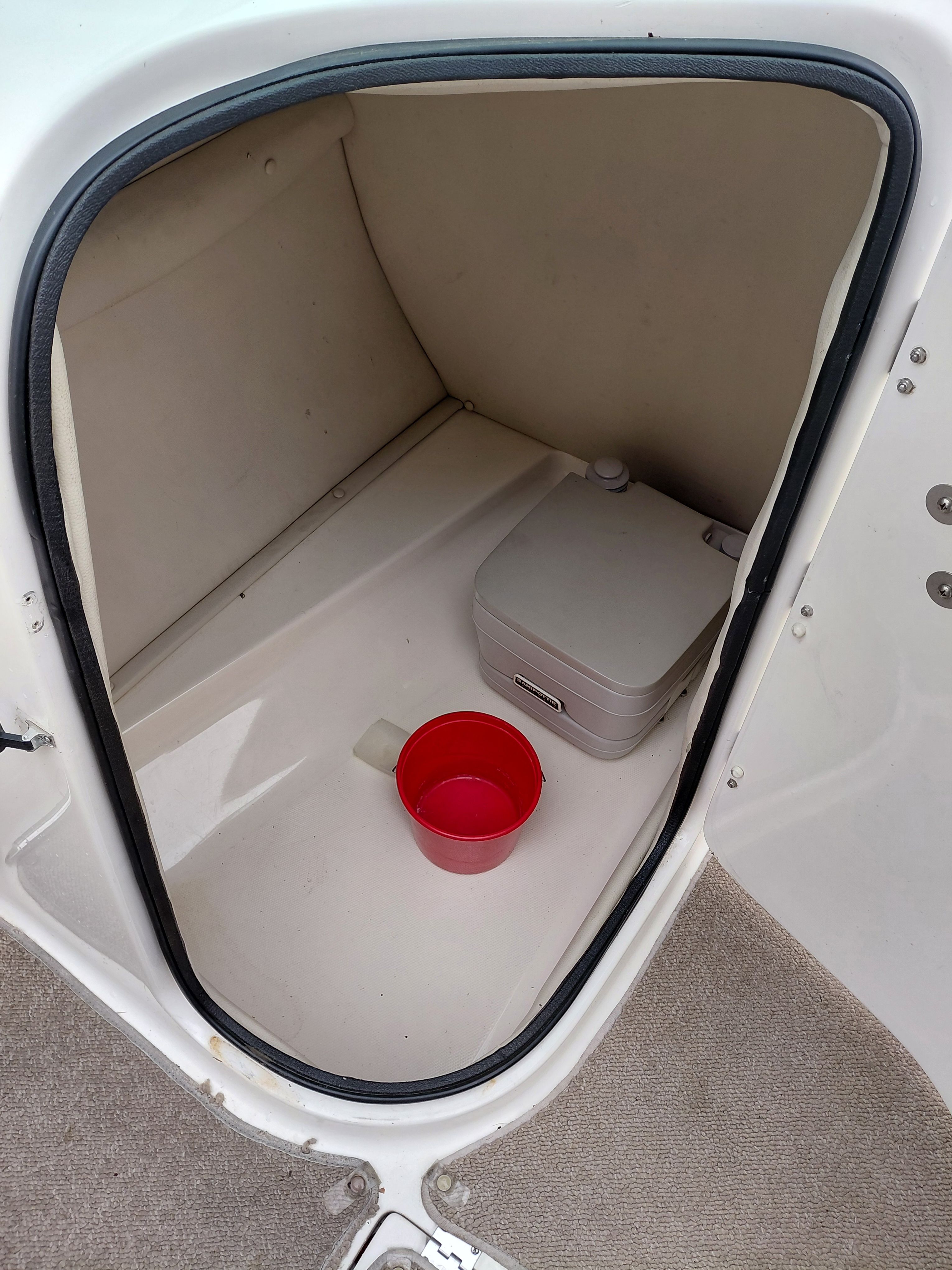 Interior of Chaparral Sunestra 254 boat, portable toilet and red bucket.