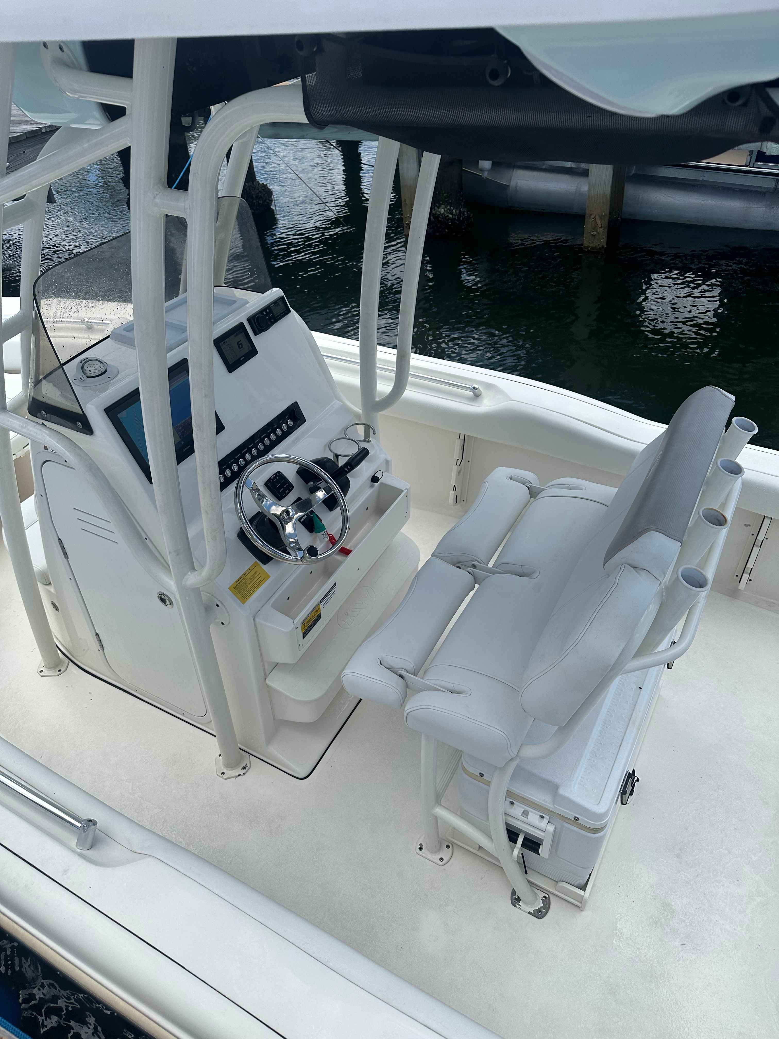 A modern boat with a helm and seating on calm water.