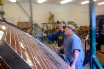 Workers restoring a 1931 Hacker-Craft 26 Dolphin boat in a workshop.