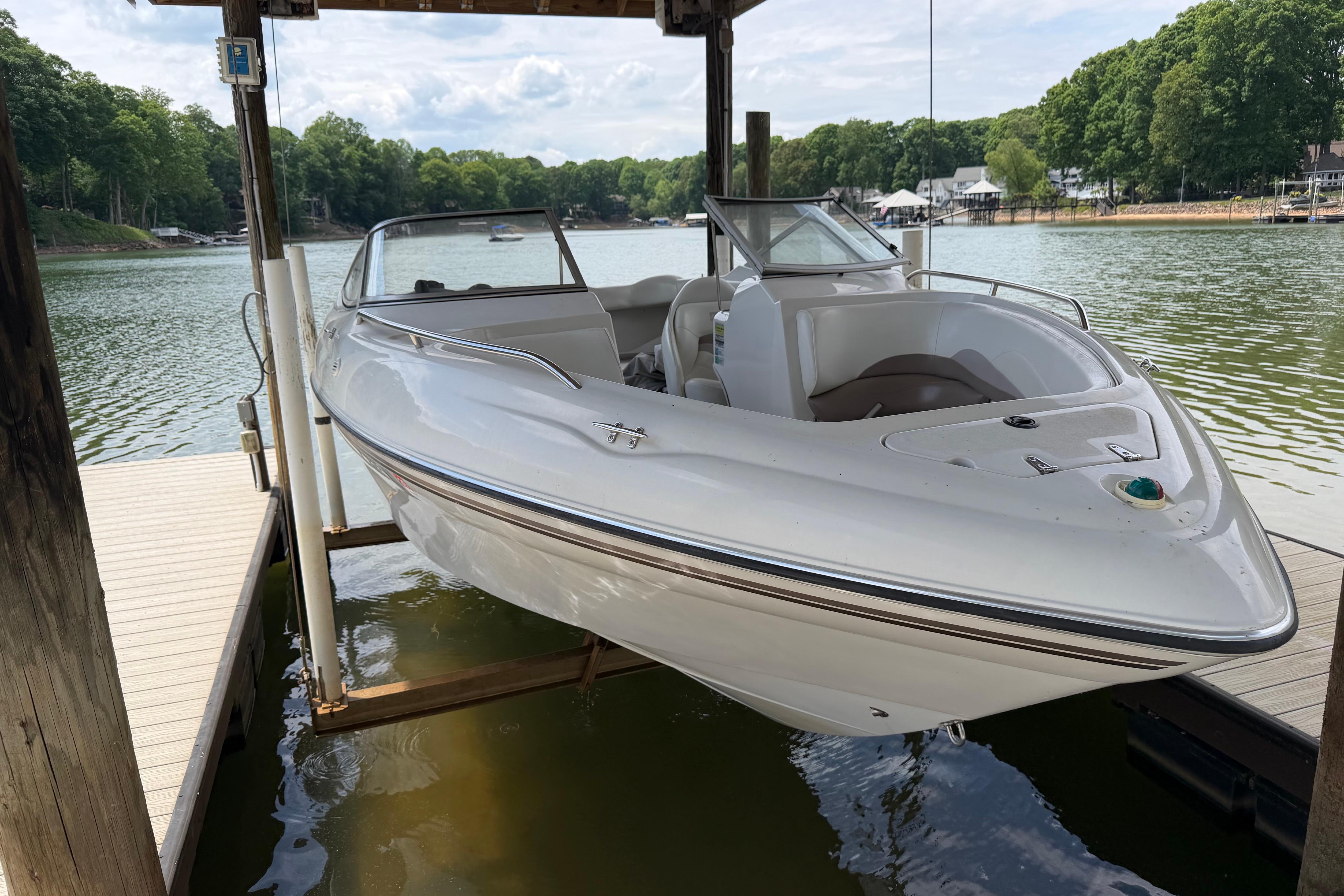 1998 Four Winns 220 Horizon boat docked on a serene lake.