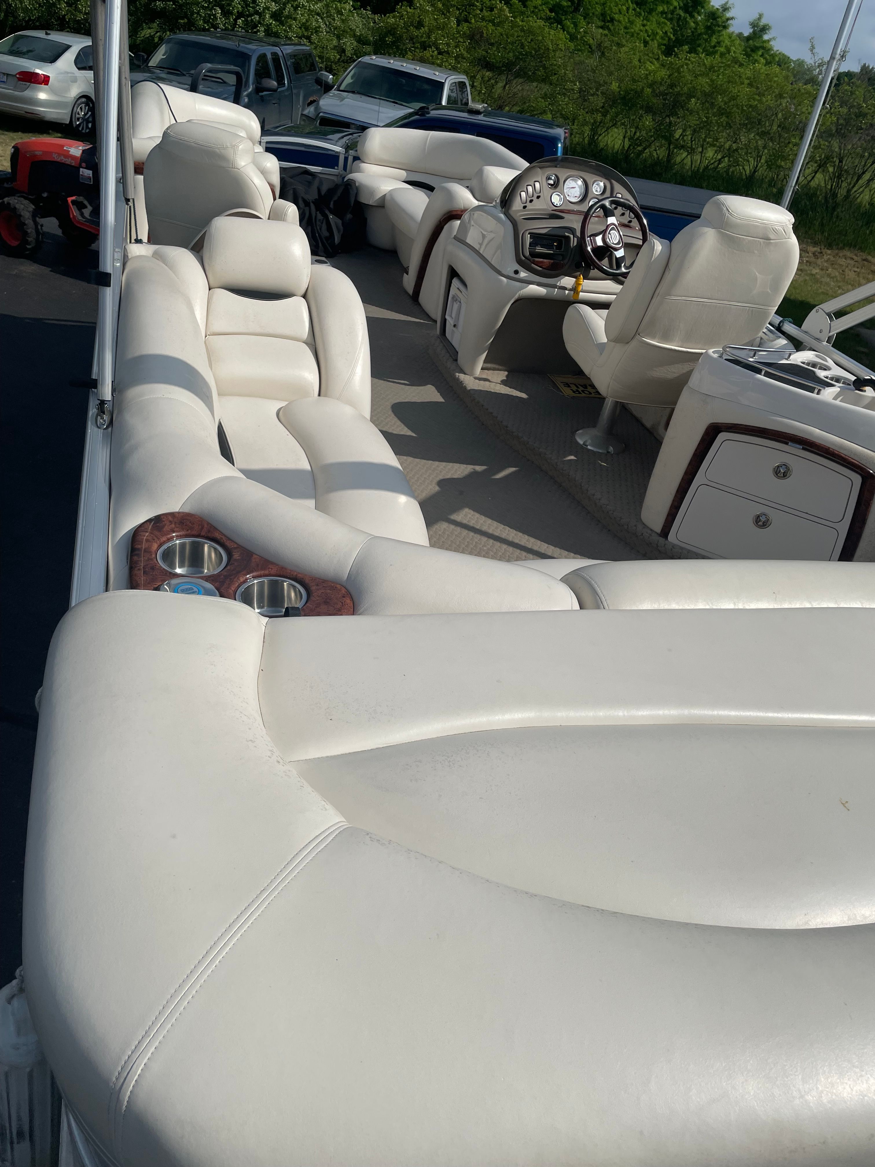 A luxurious pontoon boat with white leather seating and a sleek helm station.