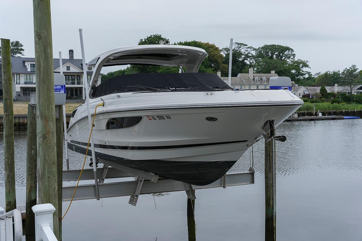 2018 Sea Ray SLX 350 boat docked on a lift by a waterfront property.