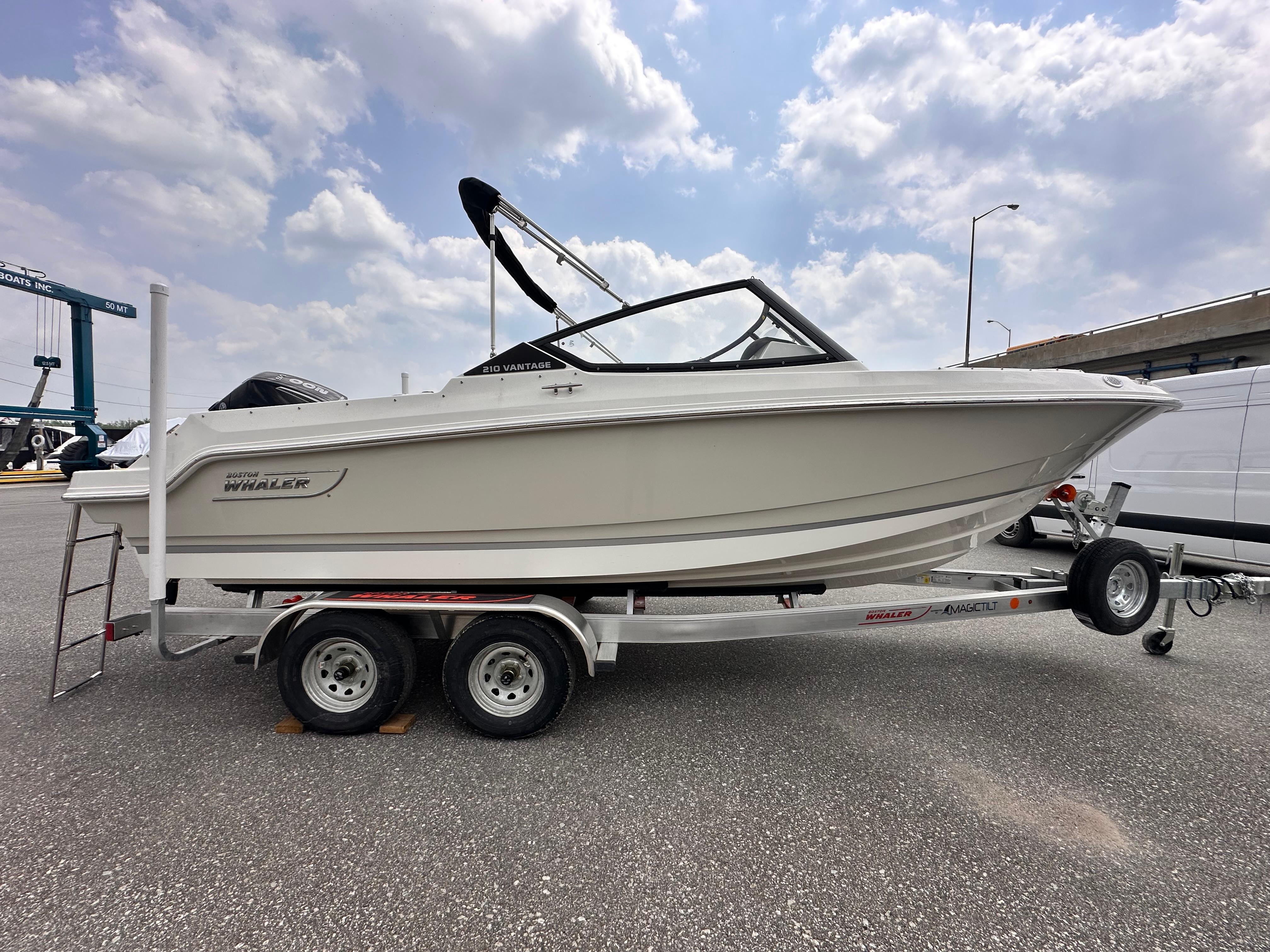 2025 Boston Whaler 210 Vantage boat on trailer under cloudy sky.