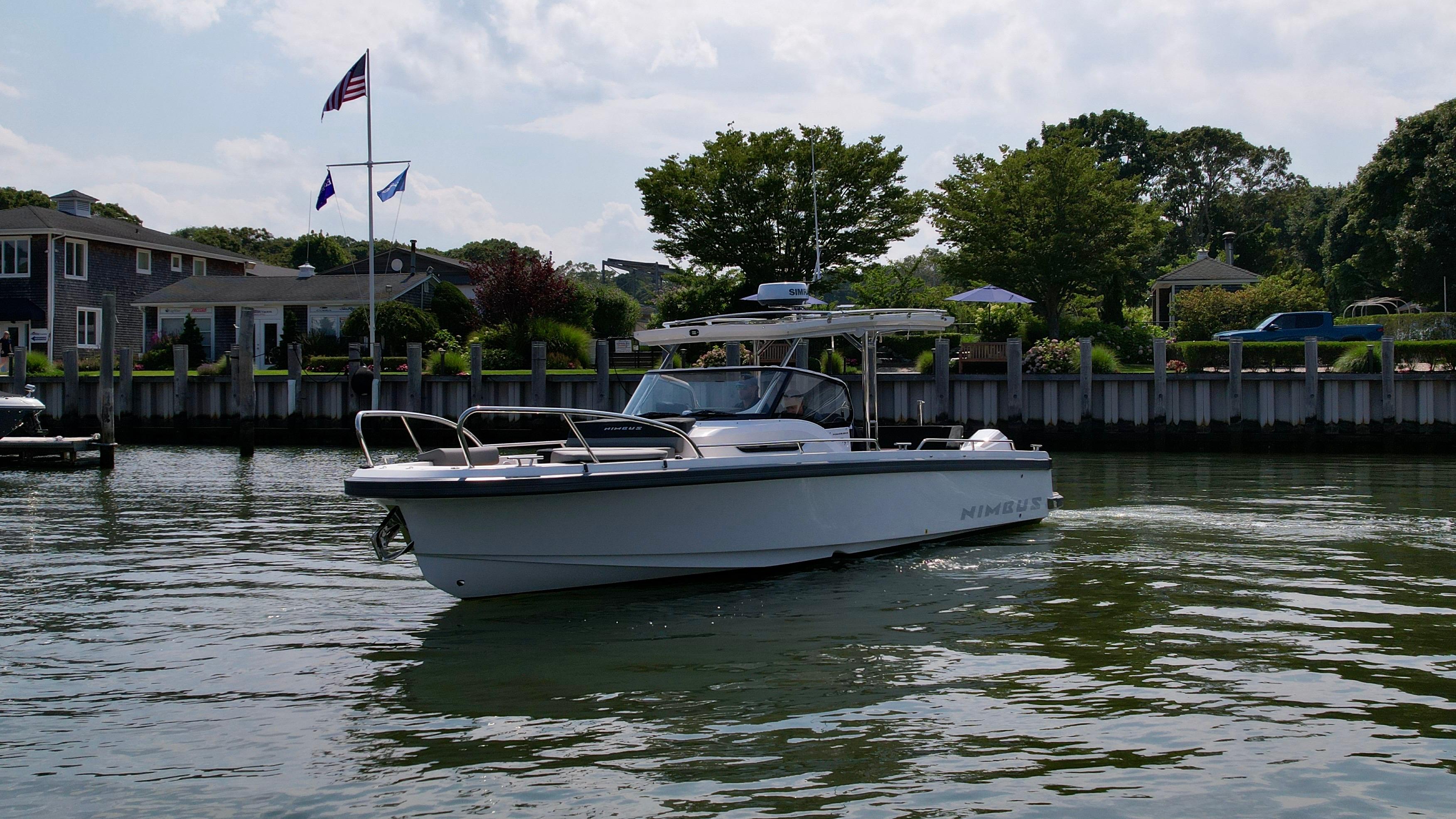 2025 Nimbus T9 boat cruising on a calm river near waterfront homes.