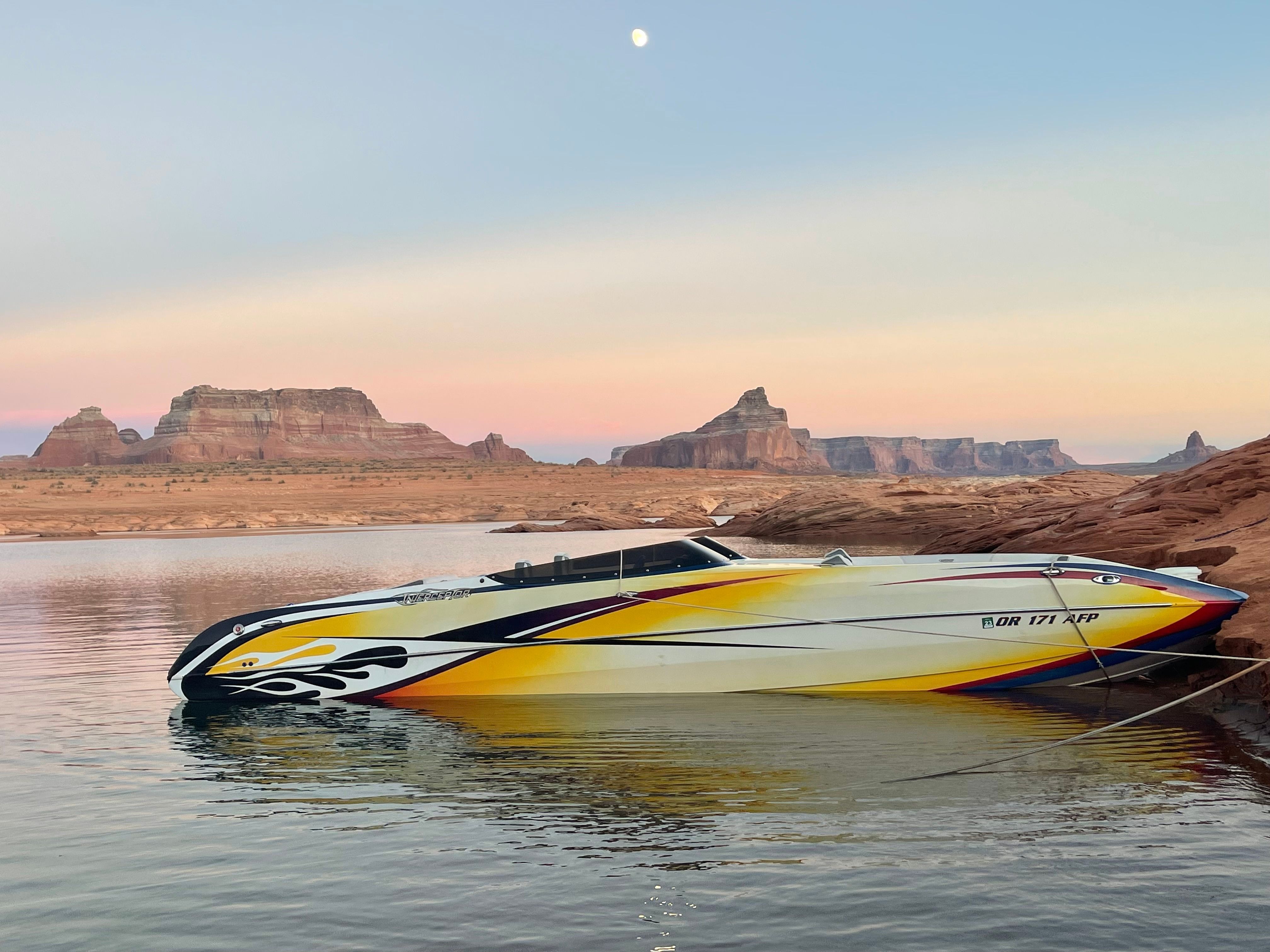 A 2016 Interceptor CoolCat boat sits in calm water against a rocky desert landscape.