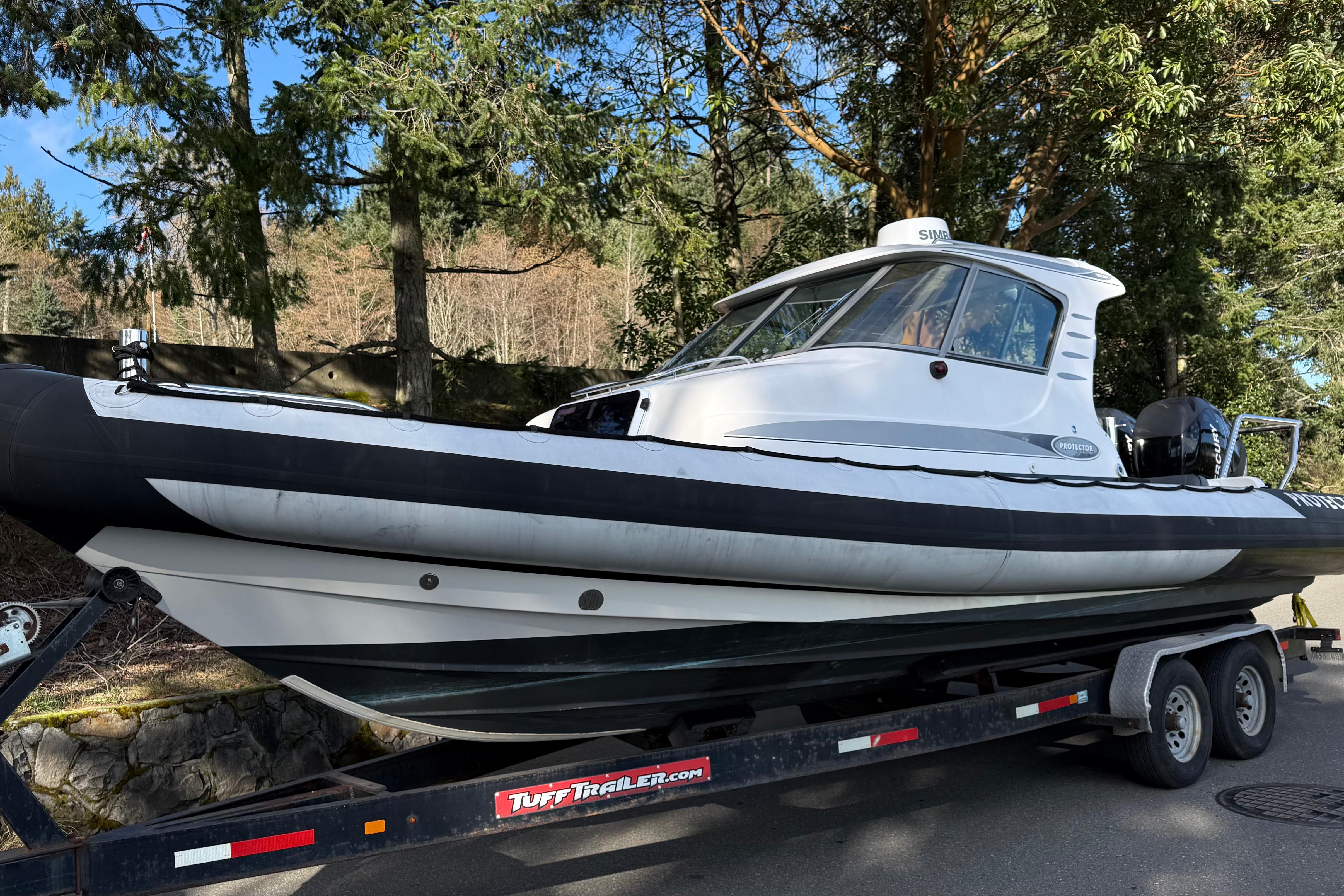 2006 Rayglass Protector Targa boat on trailer, surrounded by trees.