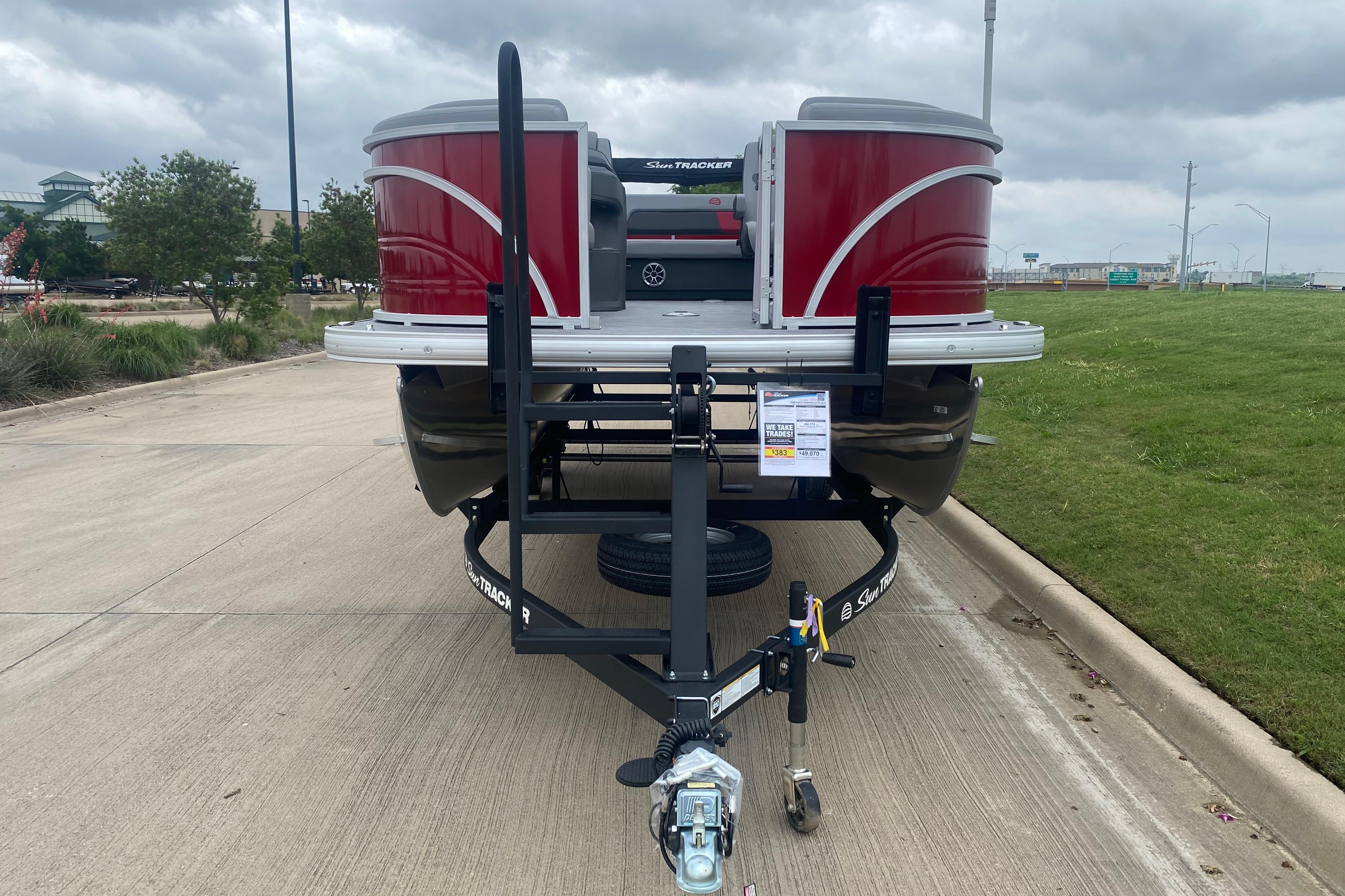 2026 Sun Tracker Party Barge 22 RF DLX on trailer, parked on concrete under cloudy sky.