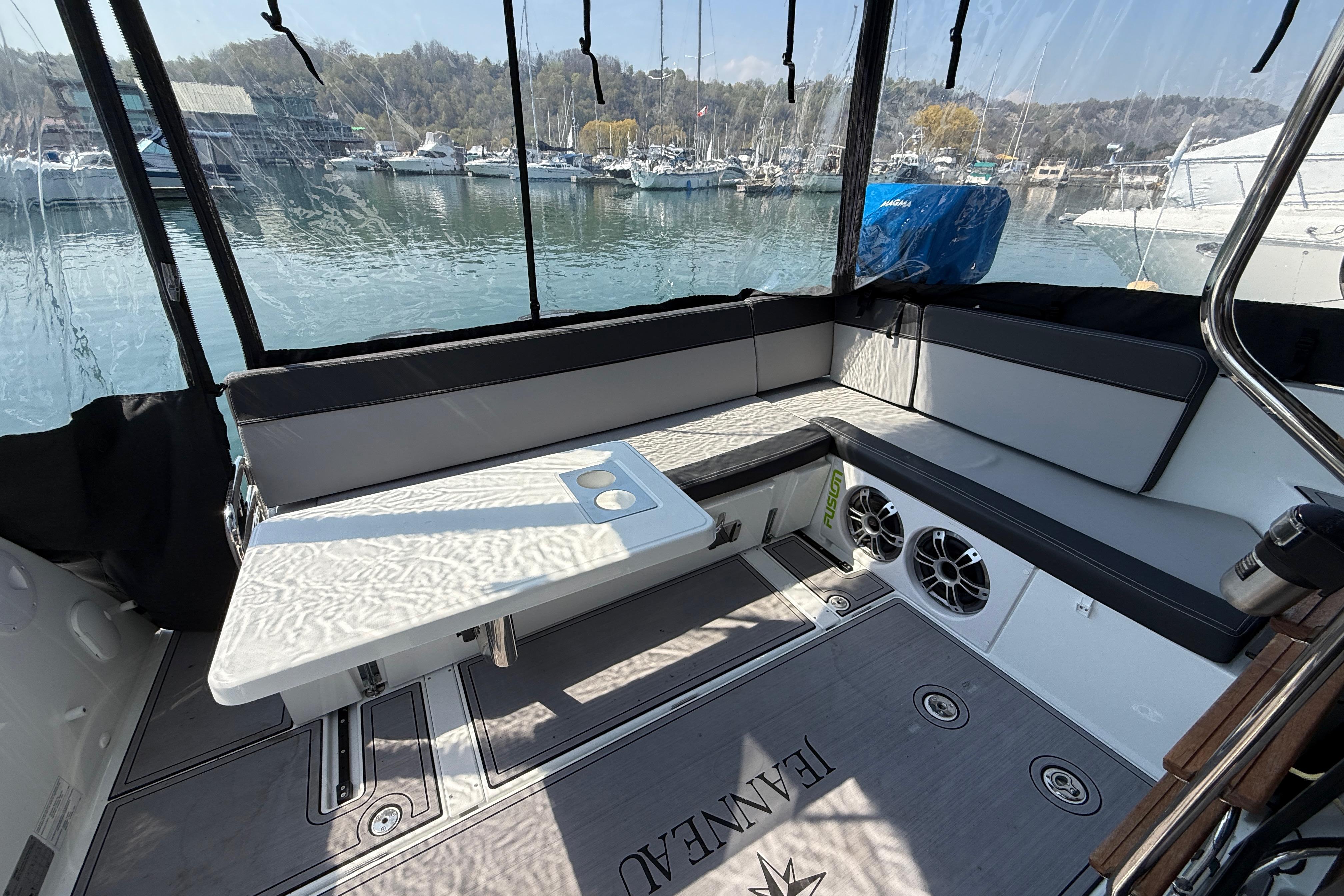 Interior of 2022 Jeanneau NC 1095 Fly boat with seating and table, overlooking marina.
