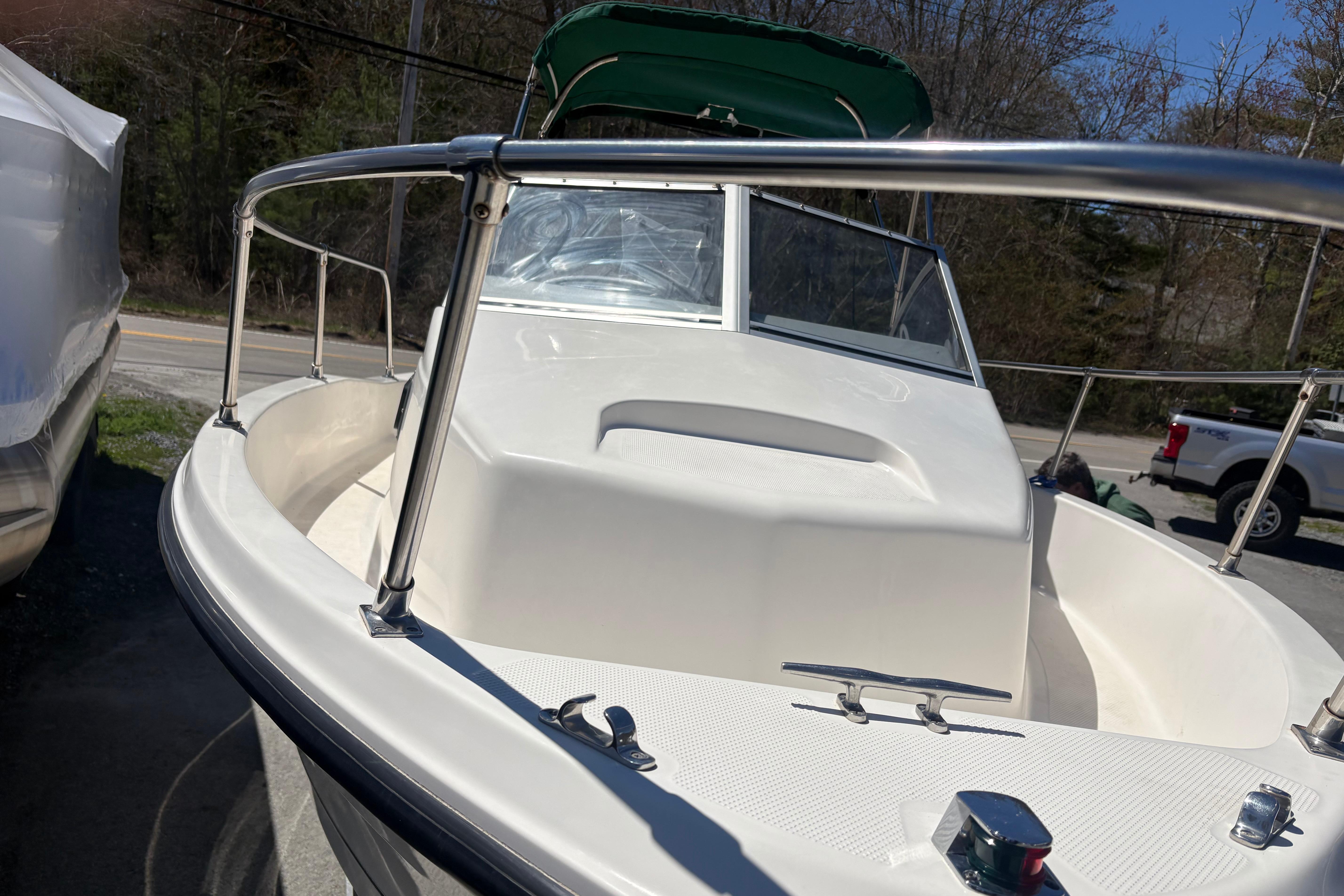 2004 Trophy 1802 Walkaround boat with green canopy, docked outdoors.