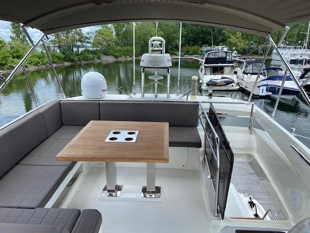 Prestige 520 Fly 2018 yacht flybridge with seating and table, docked in a marina.