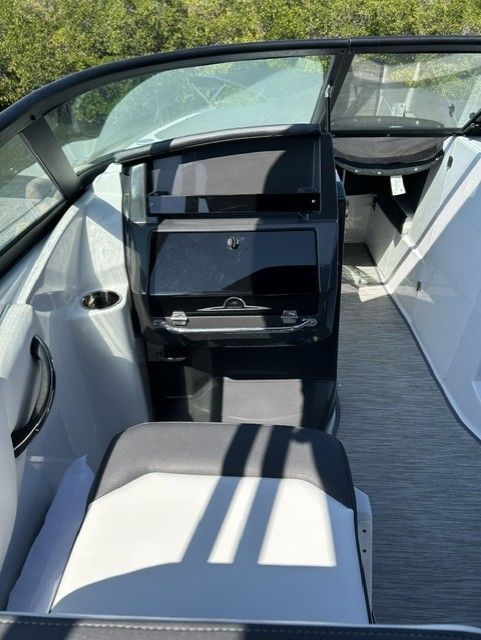 The interior of a modern boat with white and black seating and a helm station.