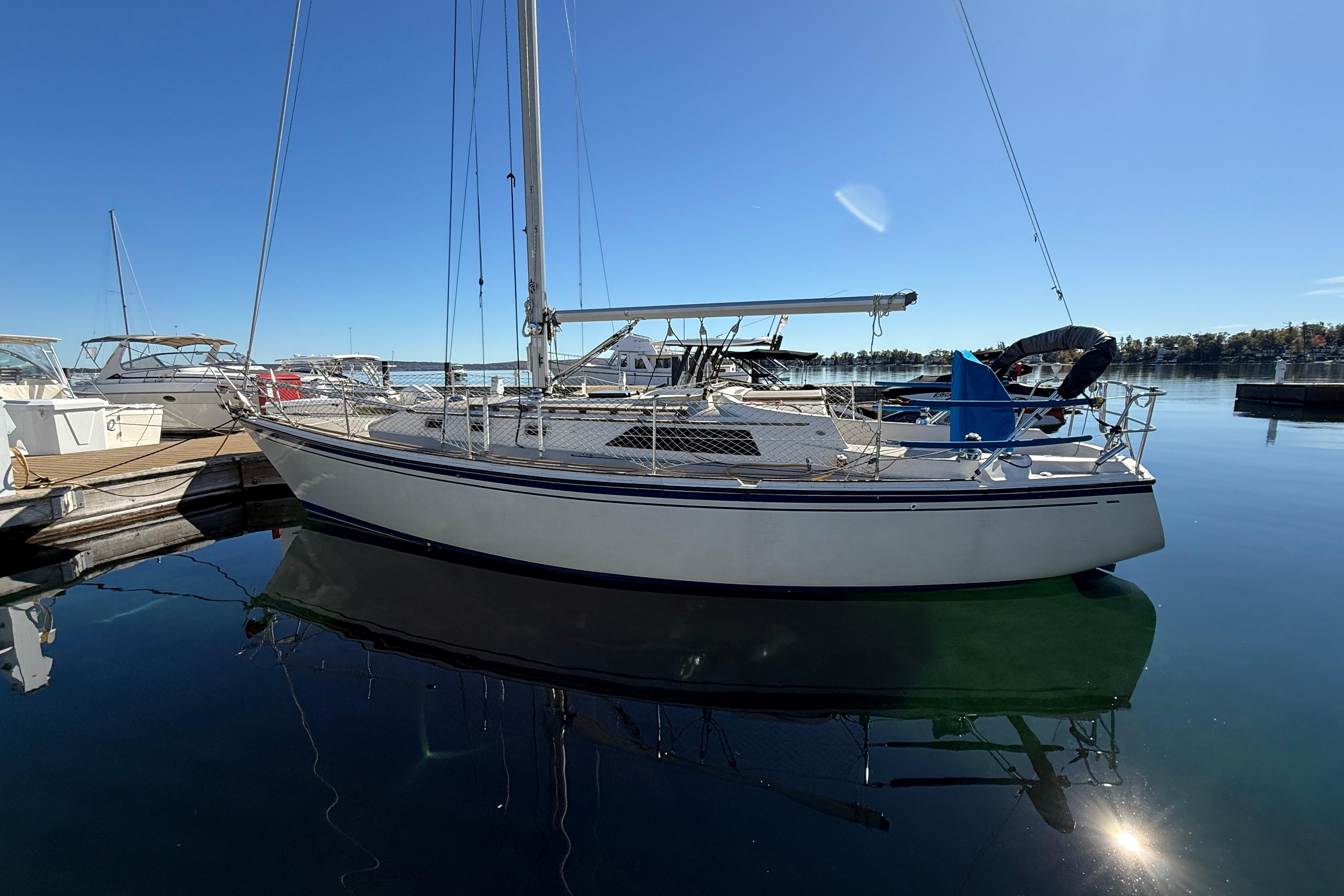 1983 O'Day 34 sailboat docked in a serene marina under clear blue skies.