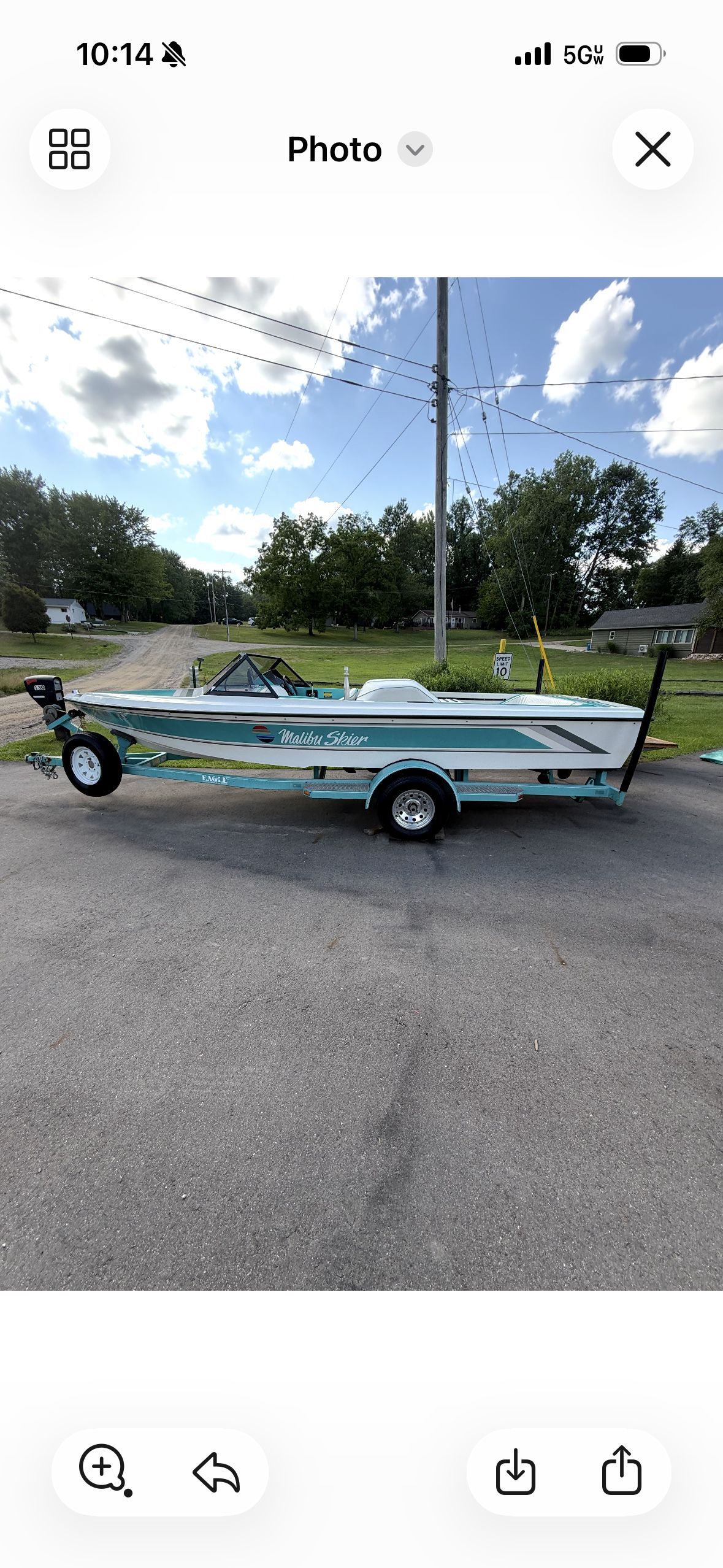 A 1992 Malibu Skier boat on a trailer, parked on a road with trees in the background.