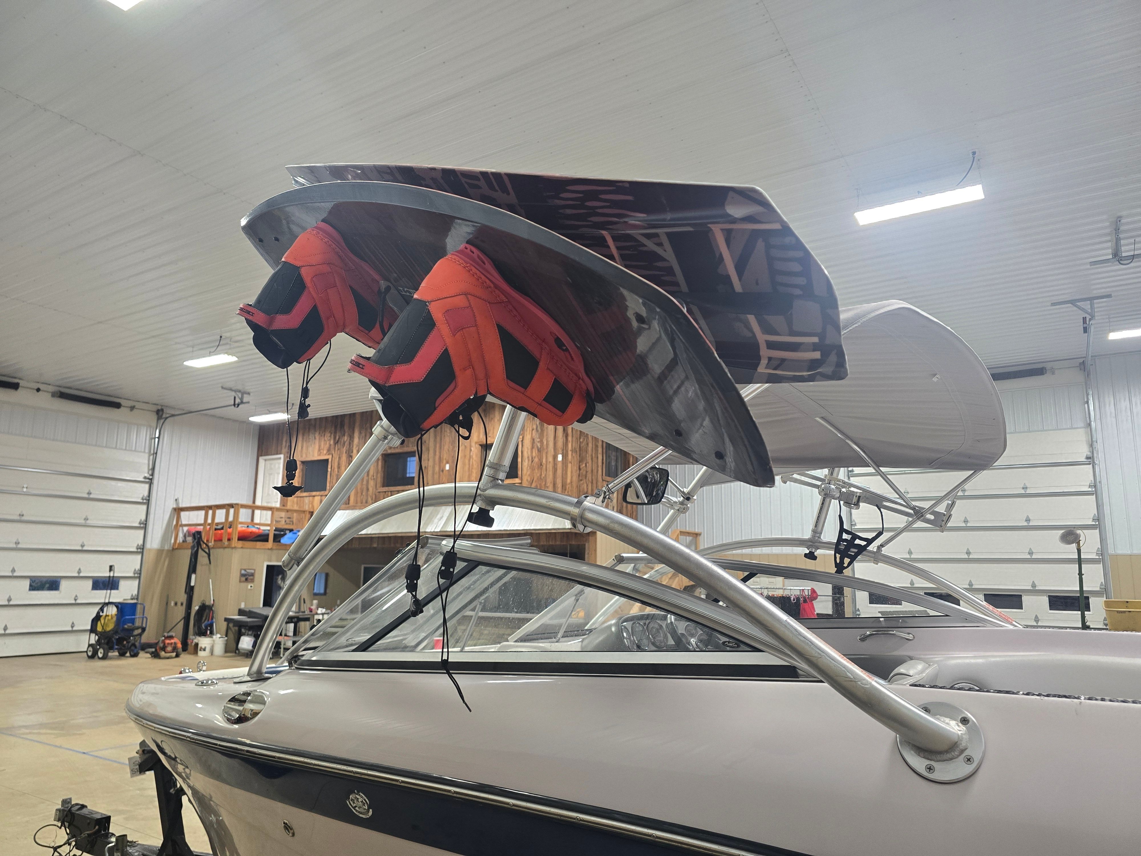 2006 Correct Craft 228 boat with wakeboard and life jackets in garage.