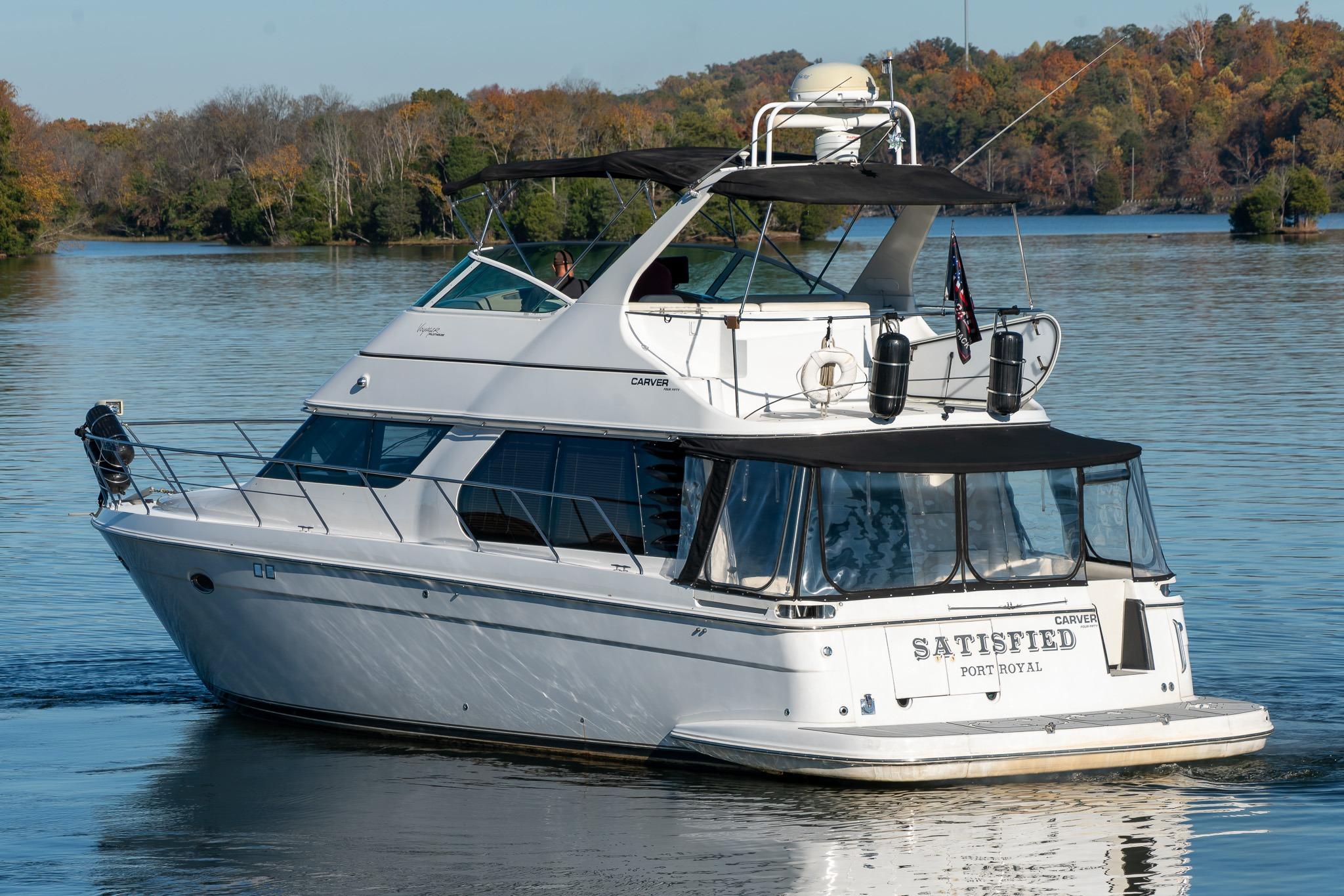 2000 Carver 450 Voyager Pilothouse yacht on a serene lake with autumn trees.