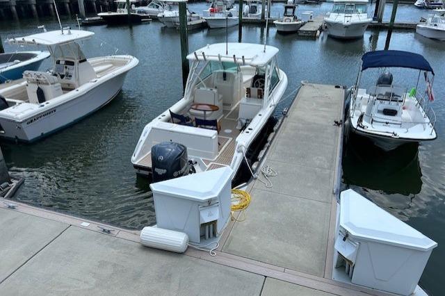 2013 Pursuit DC 265 Dual Console boat docked at a marina with other vessels.
