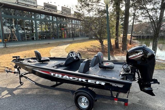 2026 Tracker Pro Team 175 boat with Mercury engine, parked near a lake and building.