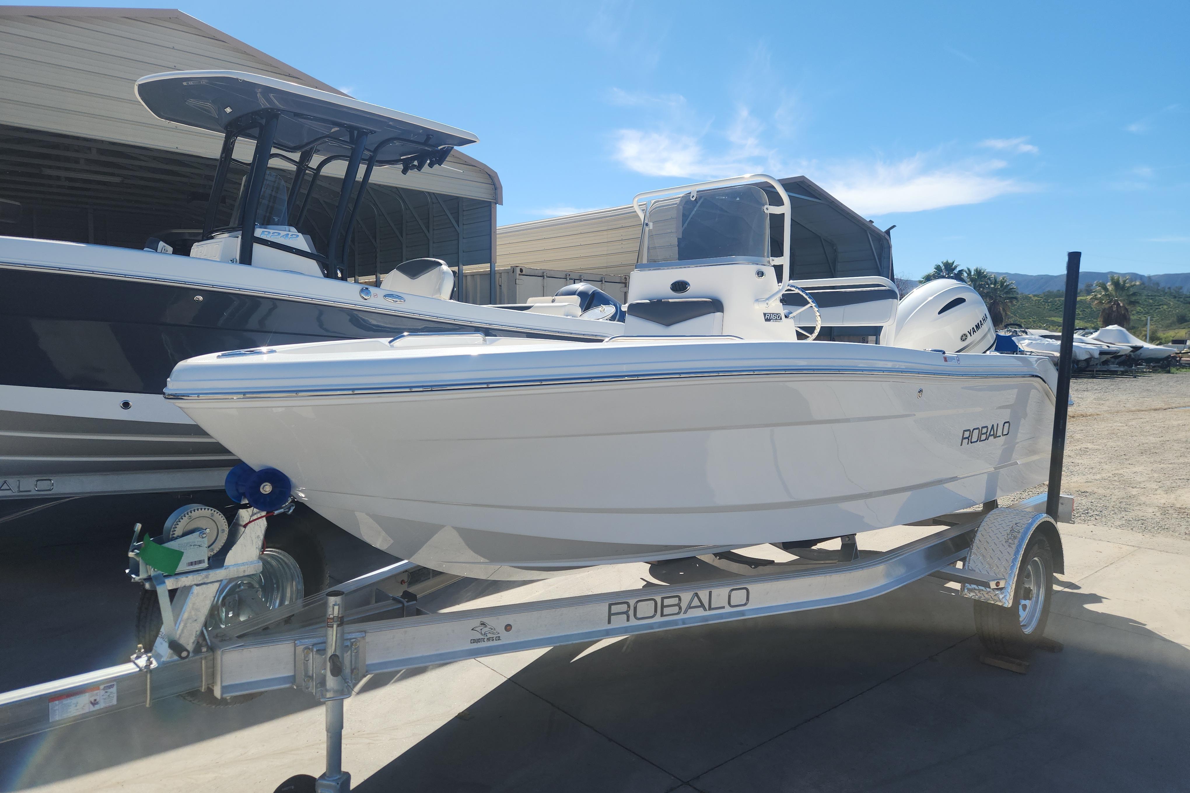 2026 Robalo R160 Center Console boat on trailer, parked outdoors under clear sky.