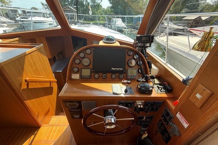 2007 Island Pilot 395 helm with Raymarine electronics and wooden steering wheel in a marina setting.