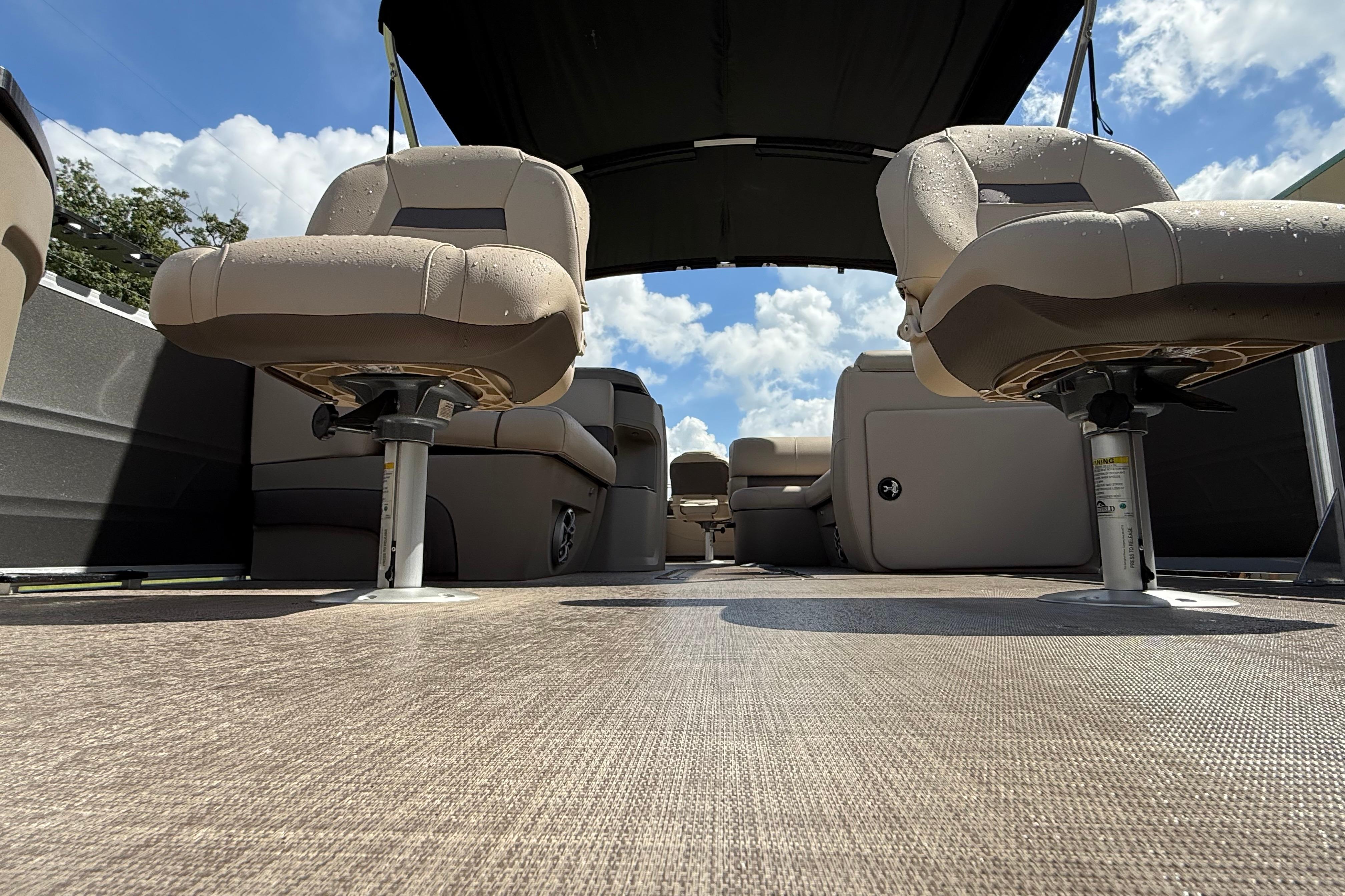 2025 Sun Tracker Fishin' Barge 22 XP3 interior with seating and canopy under blue sky.